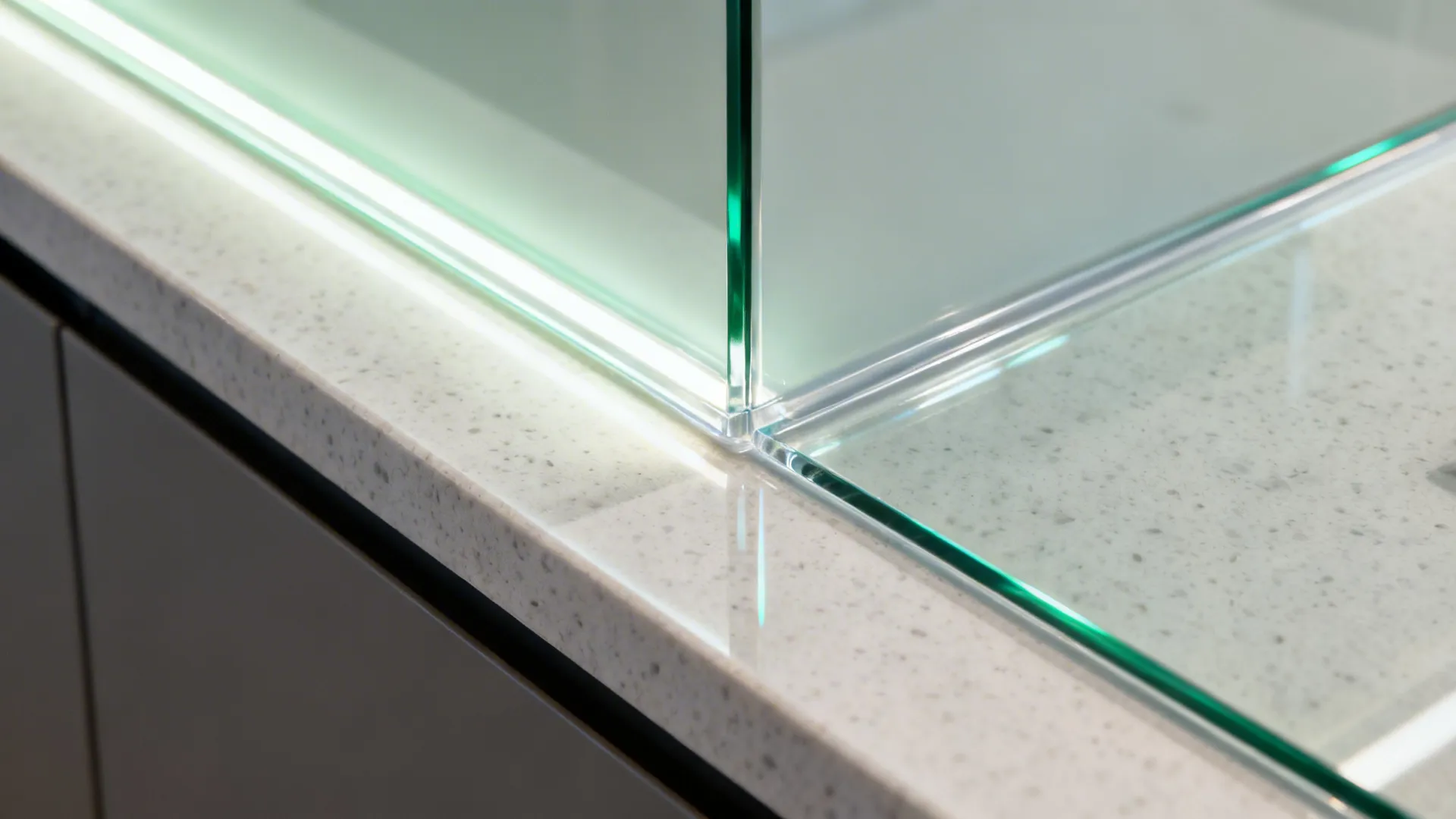 Macro of low-iron tempered glass backsplash with clean silicone joint above quartz counter.