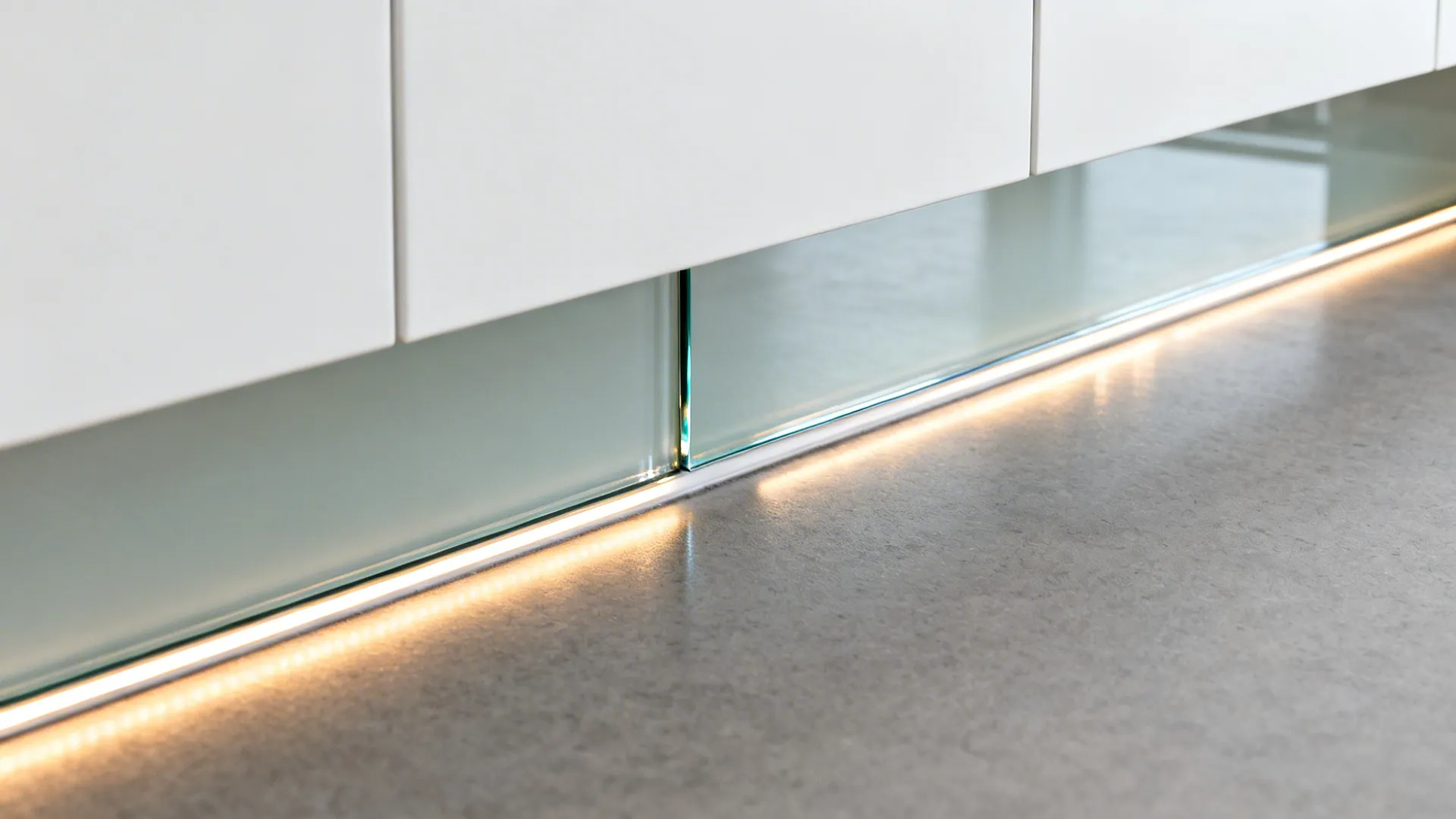 Close-up of a low-iron glass backsplash with warm under-cabinet light.
