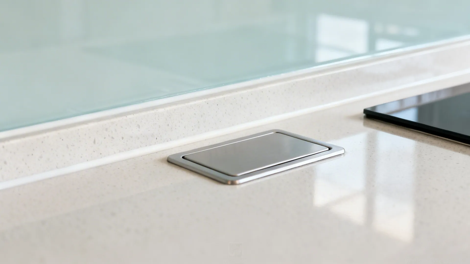 Macro of back-painted glass backsplash edge and socket cutout over light countertop