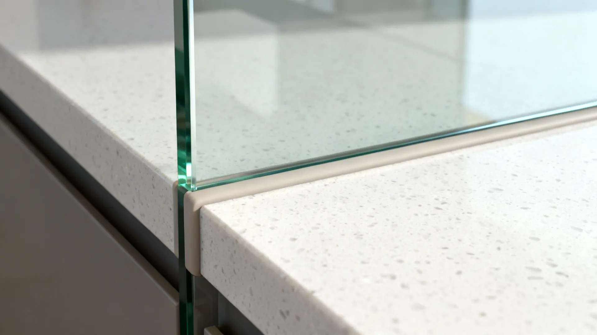 Close-up of low-iron glass backsplash edge above white quartz with neat silicone seam.