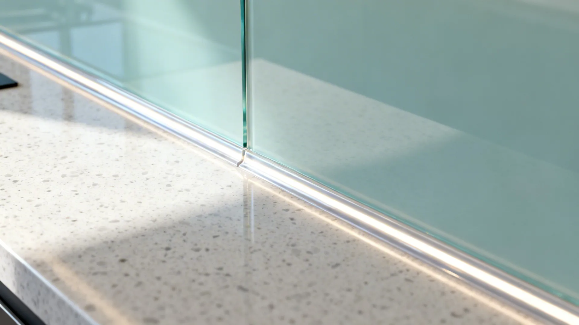 Macro view of a tempered glass backsplash edge with a clean silicone joint above quartz.