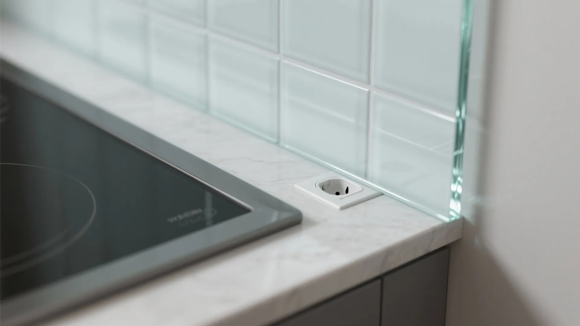 Close up of a power outlet on a marble countertop next to light blue tiles