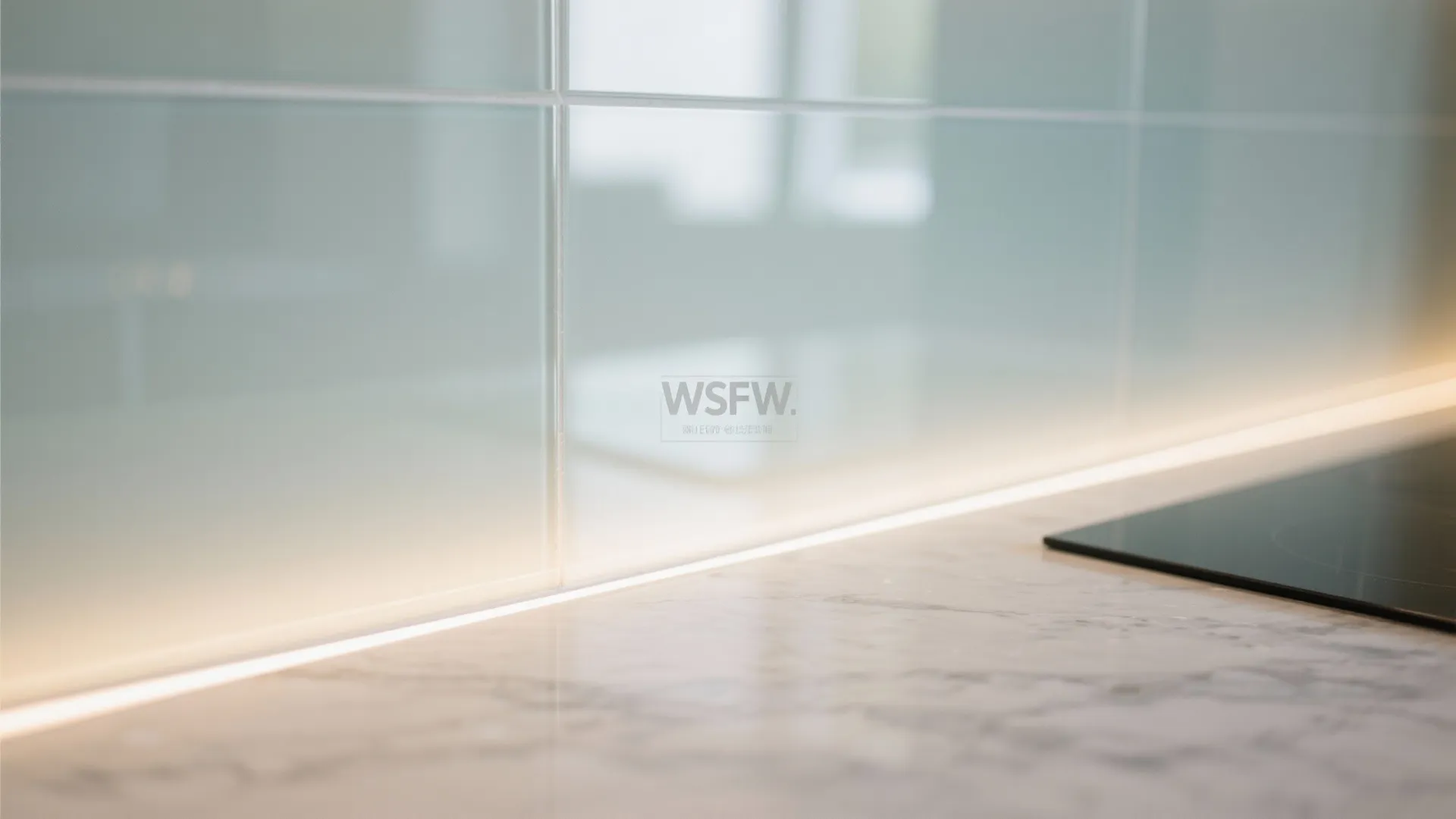 Close up of white wall tiles marble kitchen counter and warm light fixture strip below cabinets
