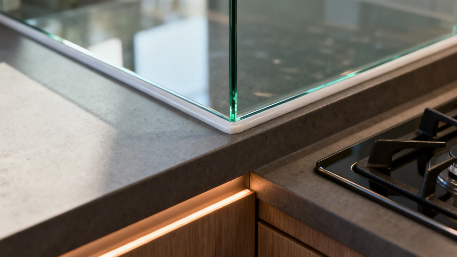 Macro of a low-iron glass backsplash edge with a clean seal and warm under-cabinet lighting.