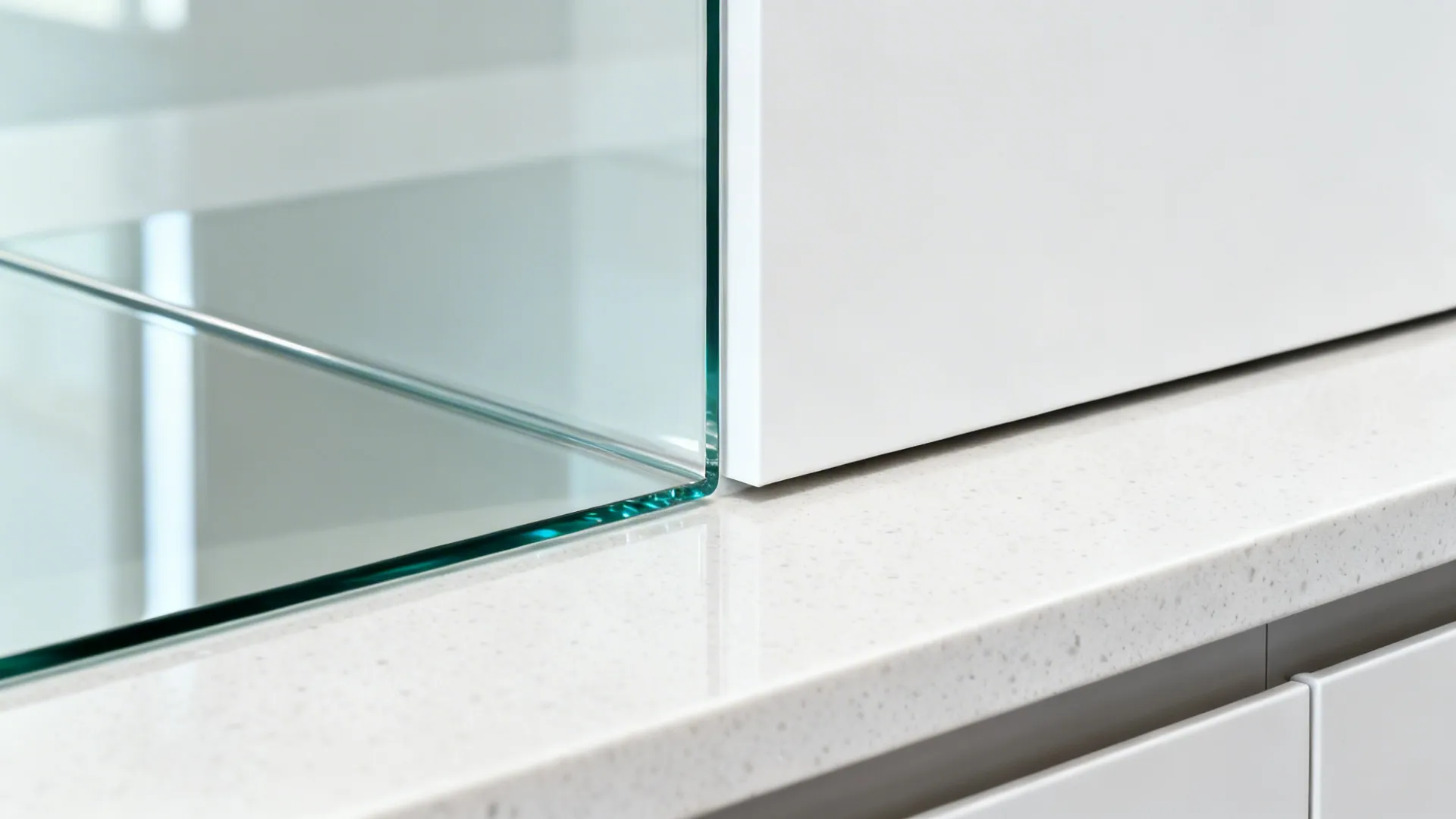 Macro of low-iron glass backsplash meeting white quartz counter with precise, clean edge.