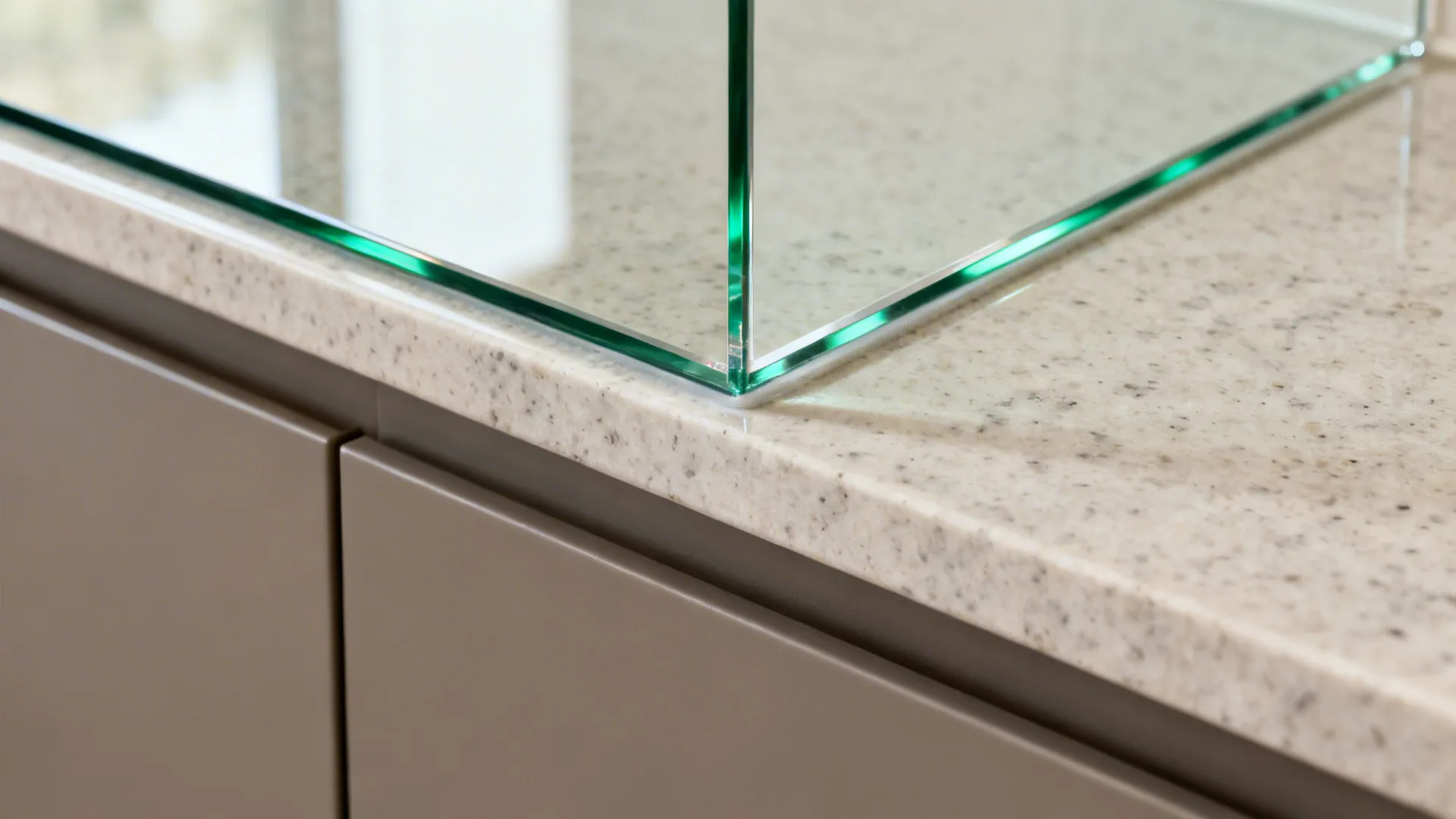 Close-up of low-iron glass backsplash edge over quartz with subtle reflections.