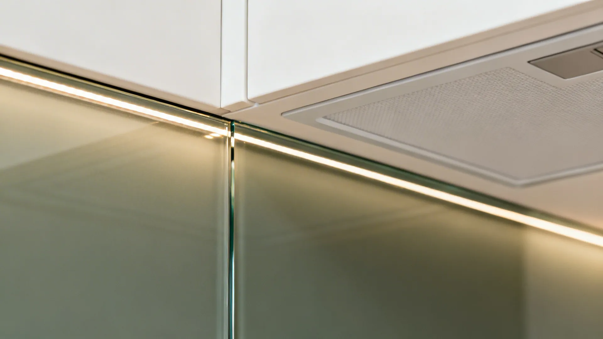 Close up view of white kitchen cabinet with led light strip and glass wall panel surface