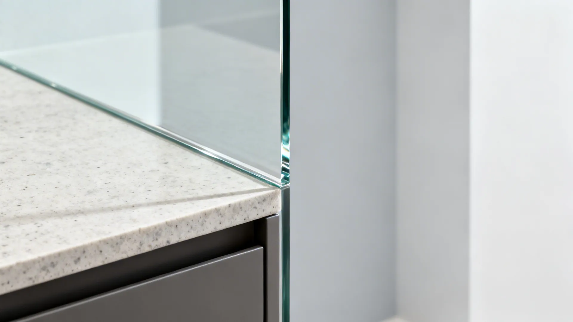 Close-up of a polished low-iron glass backsplash edge over a stone benchtop.