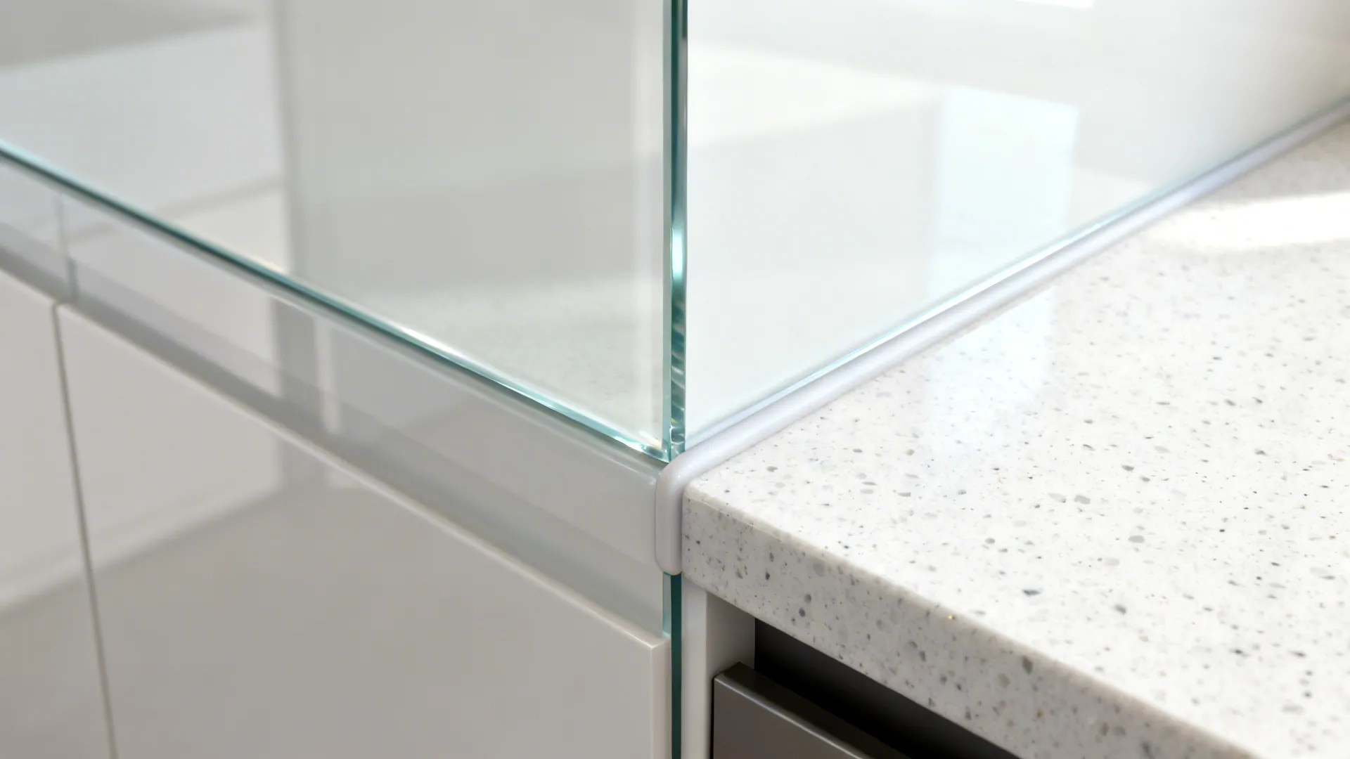 Macro of low-iron glass backsplash meeting light quartz countertop with a clean joint.