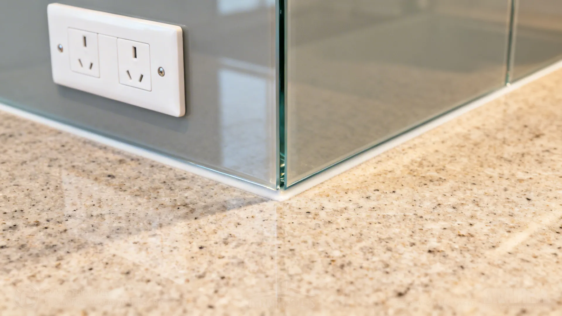 Close-up of a tempered glass backsplash with a polished edge meeting a quartz countertop.