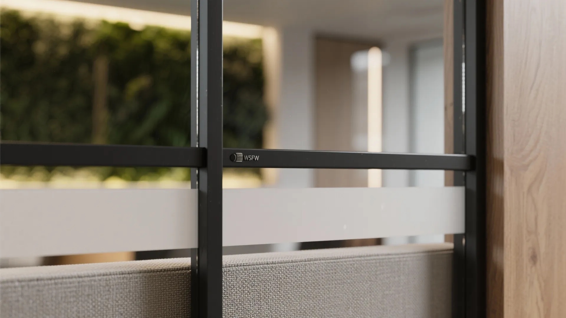 Close up of black metal glass partition frame with white privacy film and fabric sofa