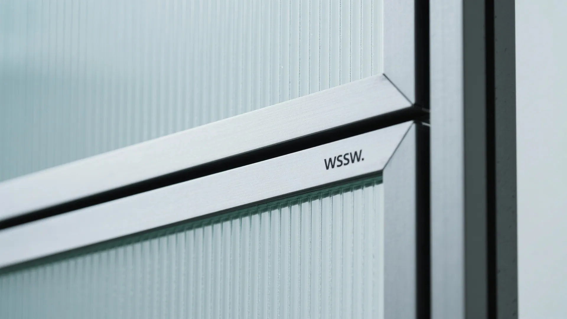 Close up of a ribbed glass panel door with a black metal frame and small logo