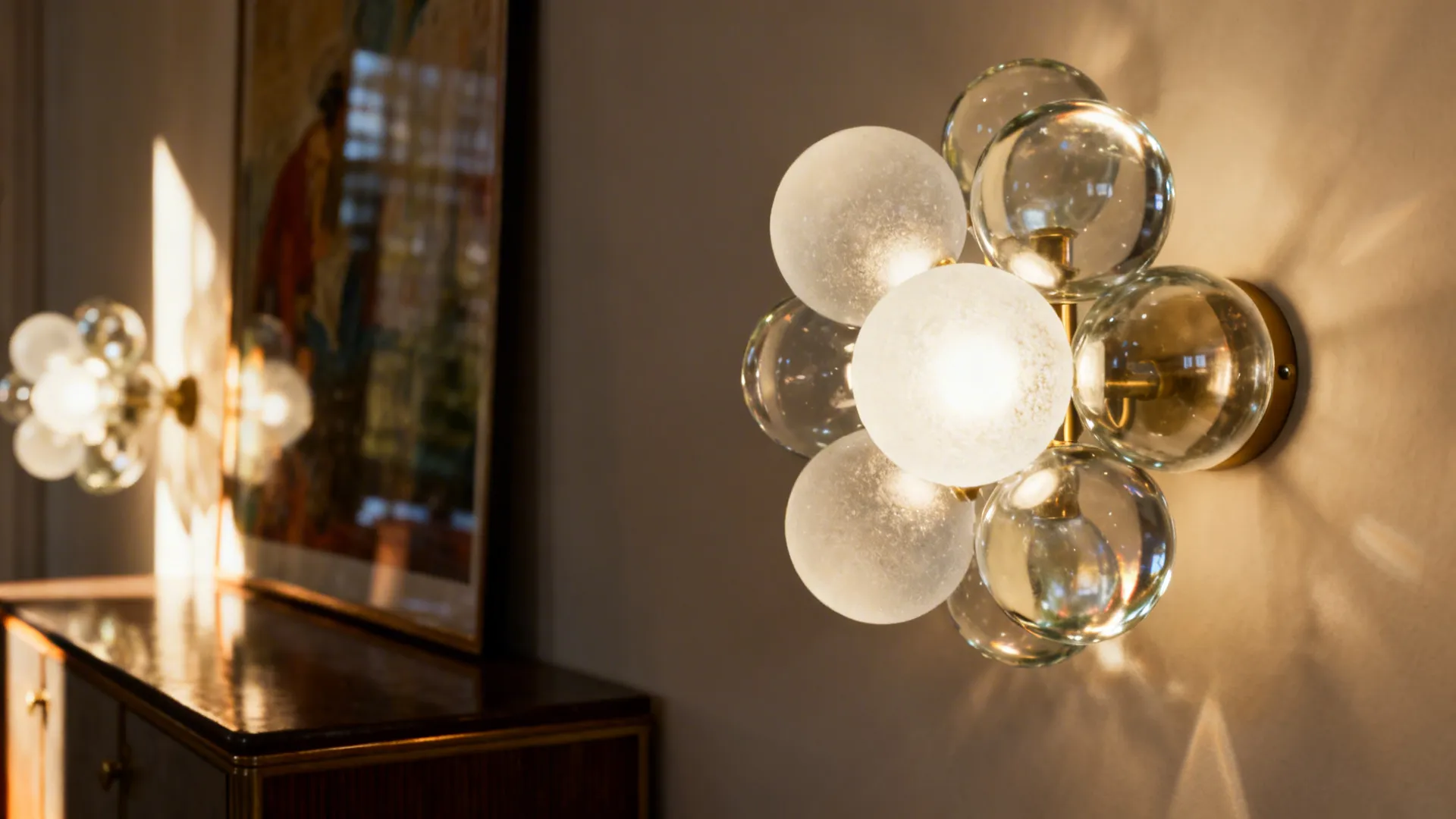 Glass globe sconces diffusing warm light over a console and artwork with mid-century style.