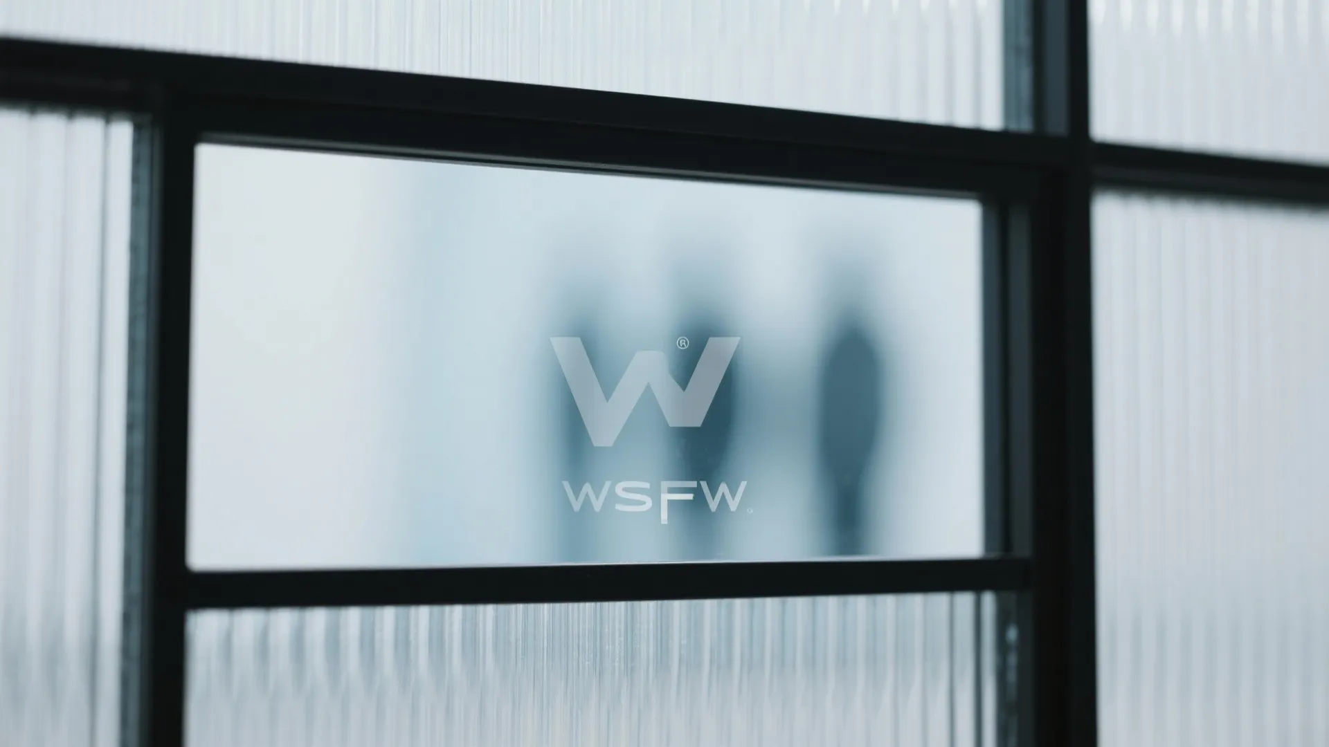 Close up view of frosted glass windows with black frames and a grey company logo