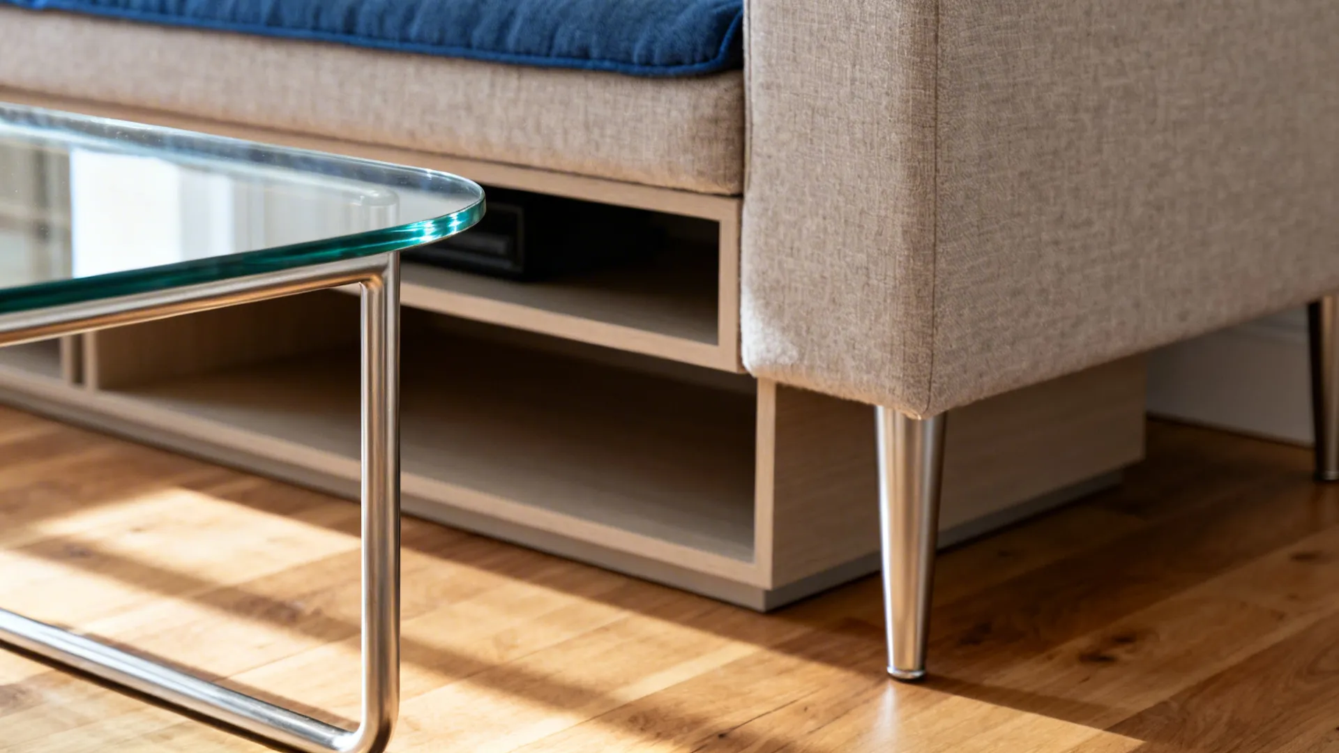 Close up of glass coffee table with metal legs next to light grey fabric sofa