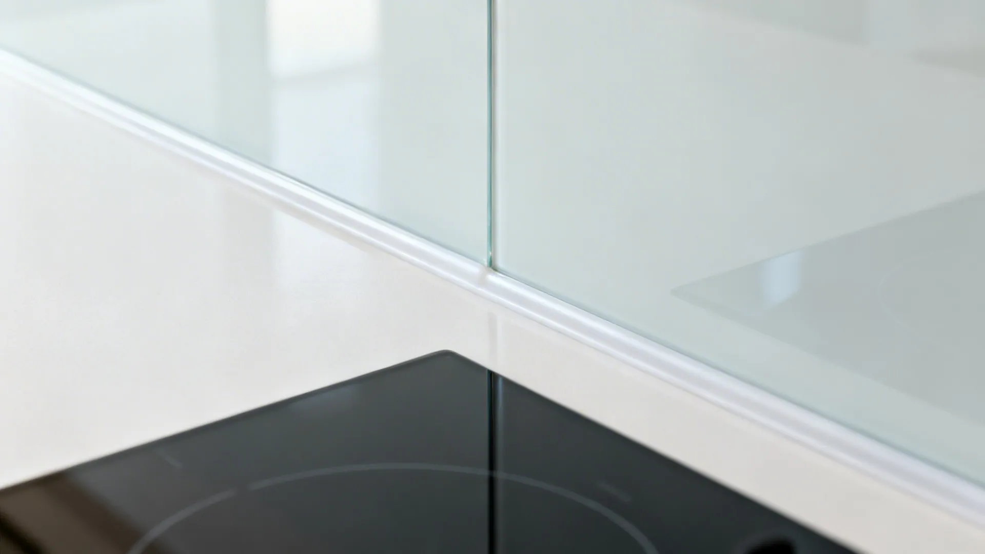 Macro of a glass-look backsplash panel edge with a neat color-matched silicone joint.