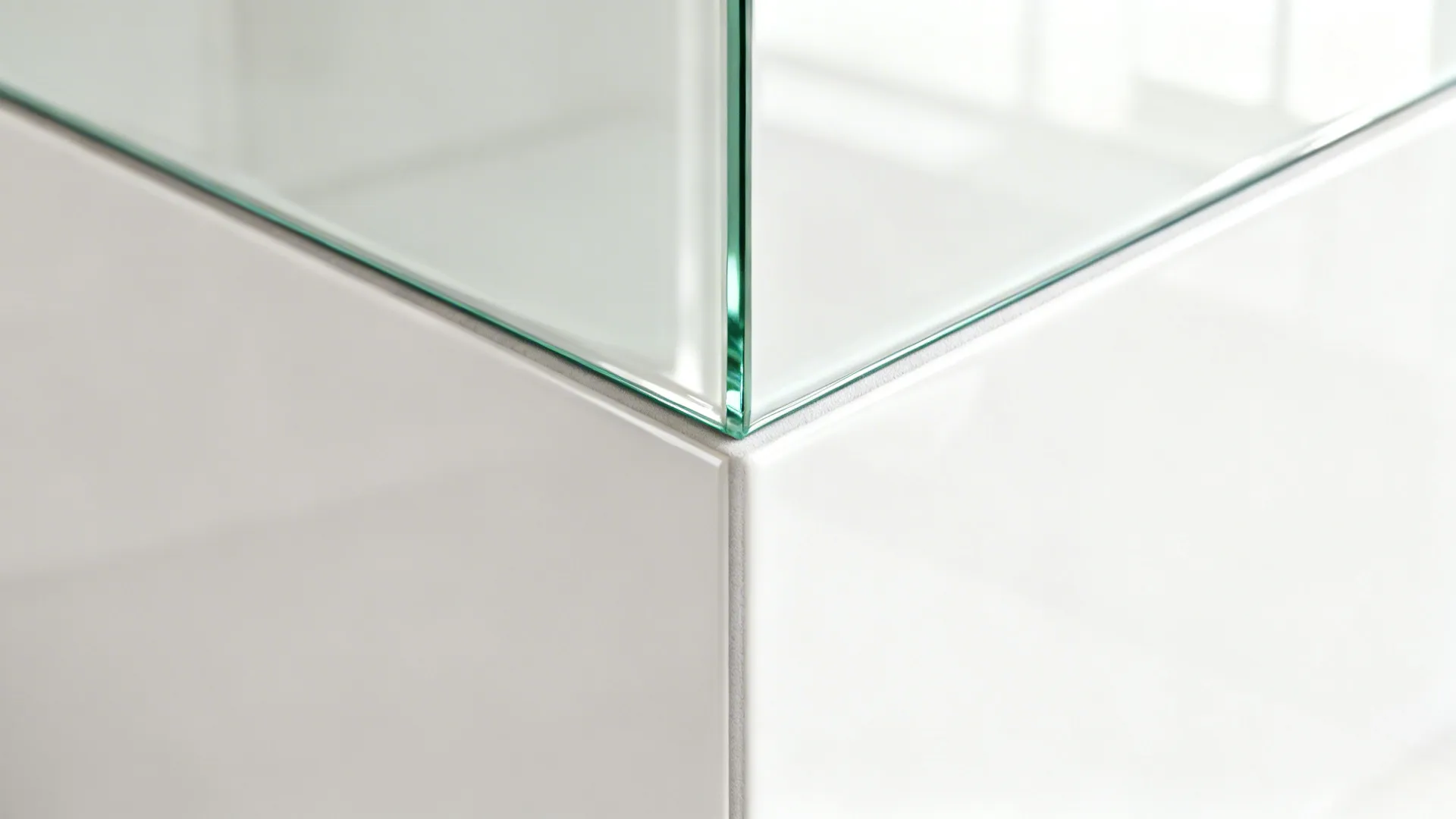 Macro of low-iron glass backsplash meeting a porcelain wall panel with a clean joint.
