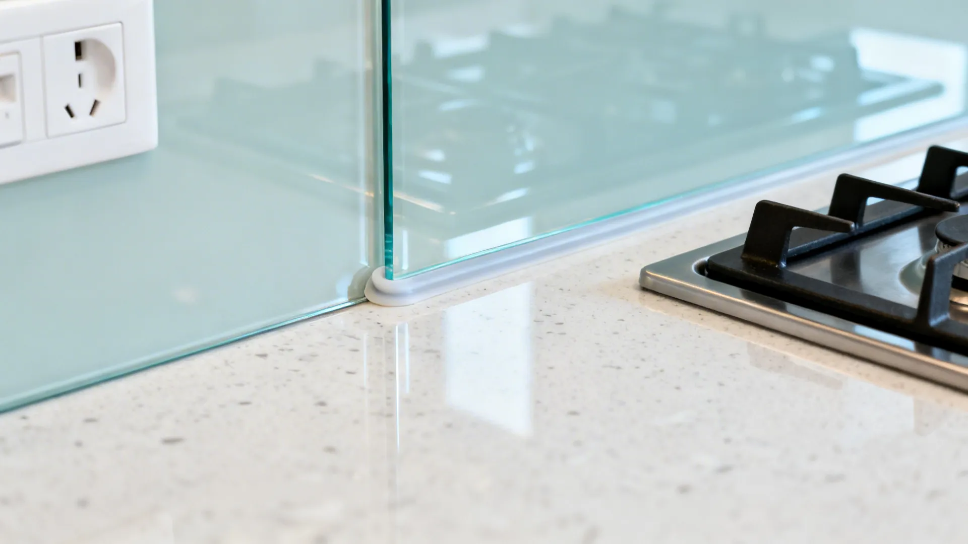 Macro of tempered glass backsplash edge with silicone spacer and clean reflective surface.