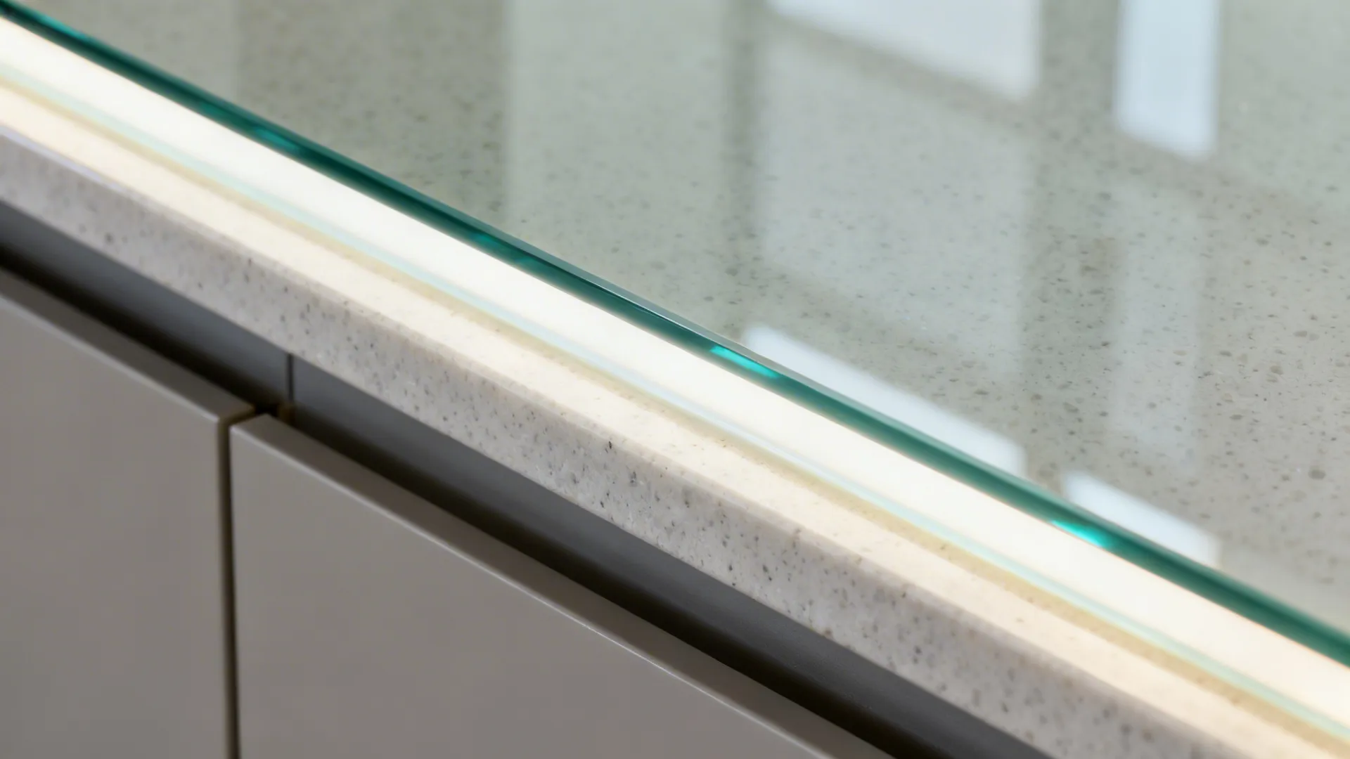 Close-up of low-iron glass backsplash edge meeting a quartz countertop under soft LED light.