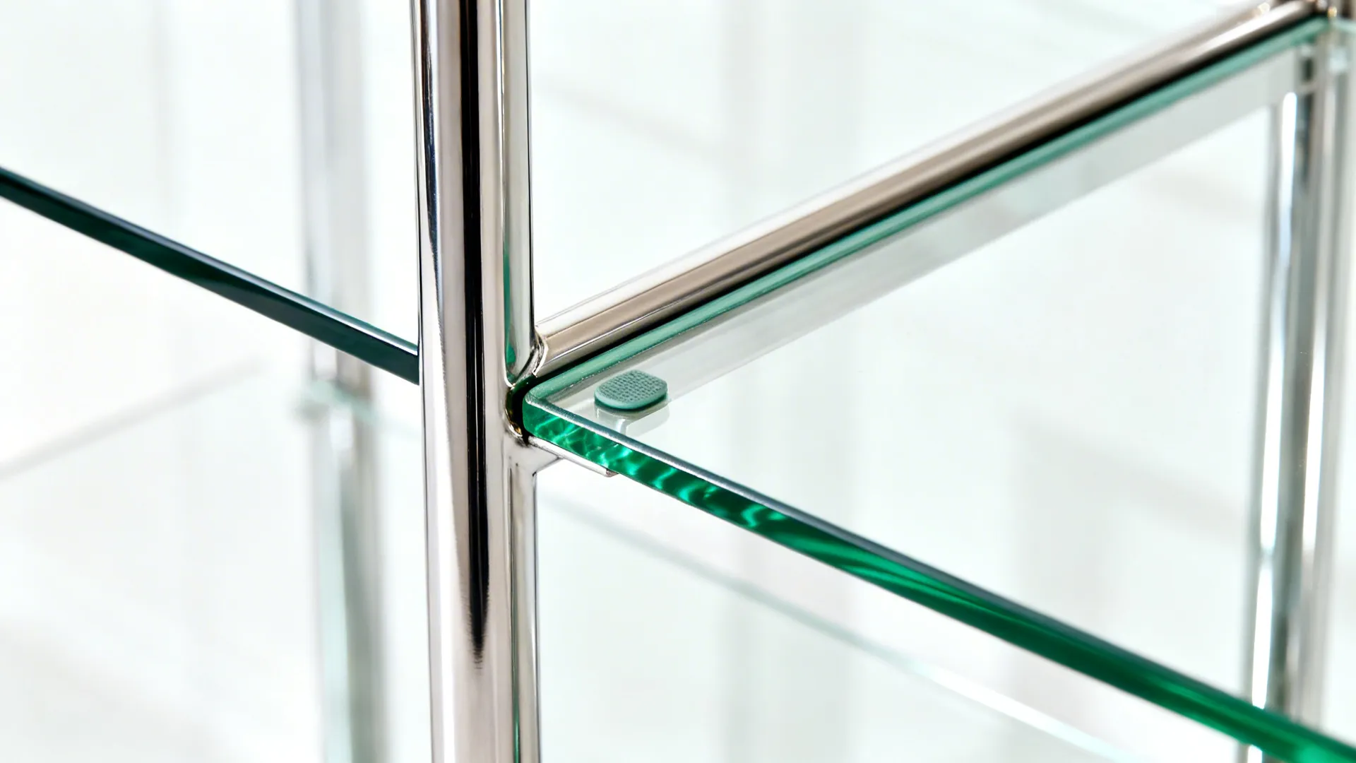 Detailed view of a modern glass shelf with chrome metal frame and small green rubber pads