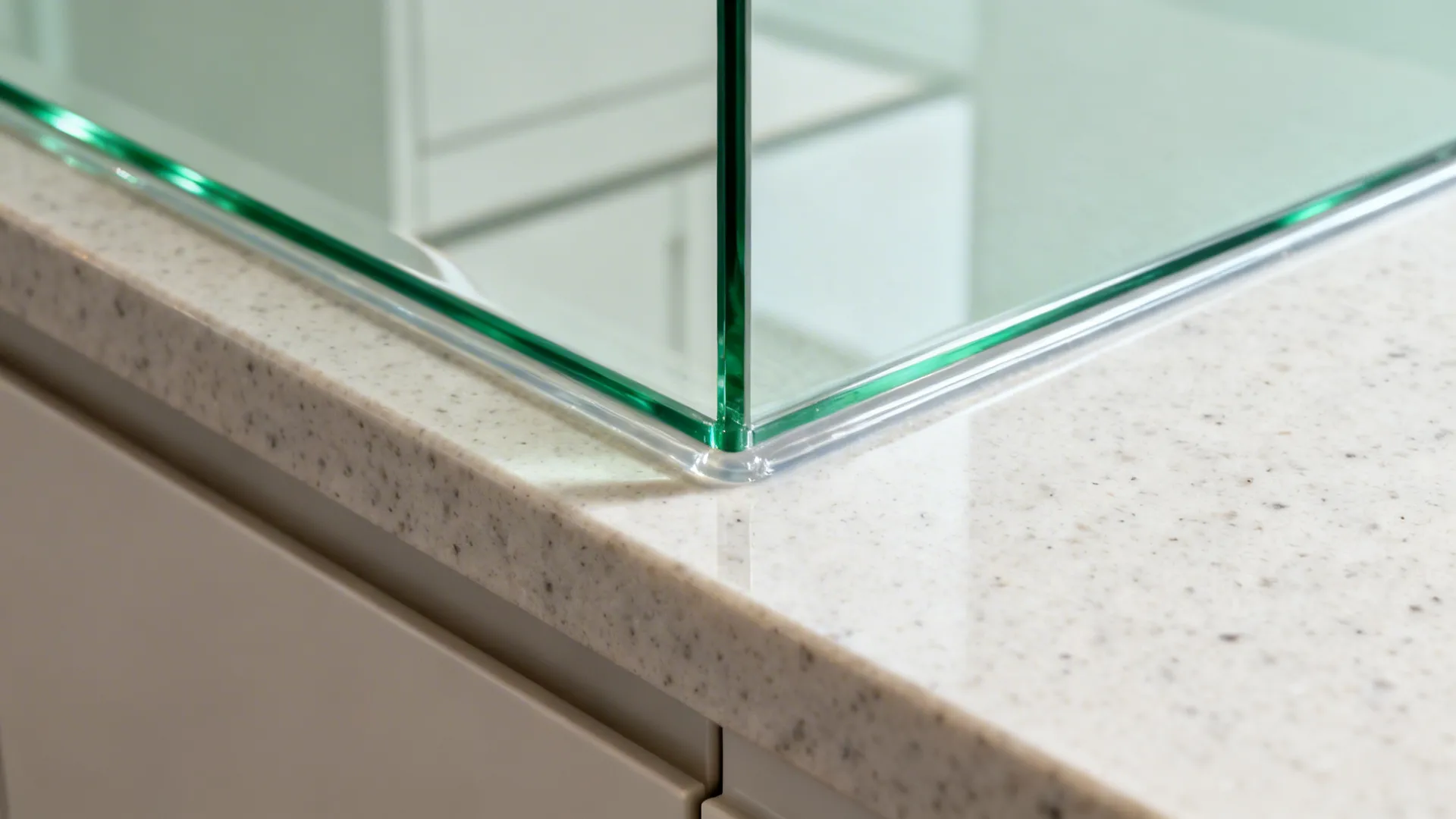 Glass panel corner sitting on a white speckled stone countertop with a protective clear seal