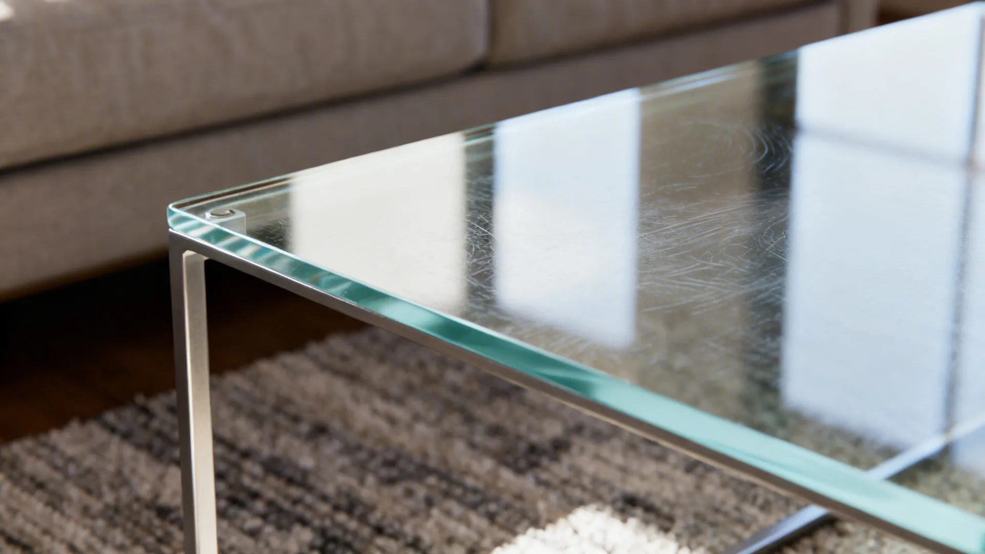 Tempered glass top on a slender metal frame end table reflecting soft daylight.