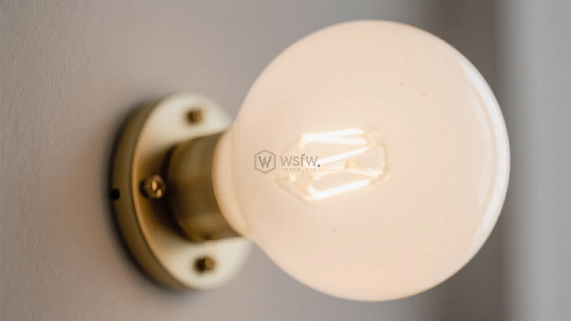 Close up view of a round glass wall light with a warm glow and brass base