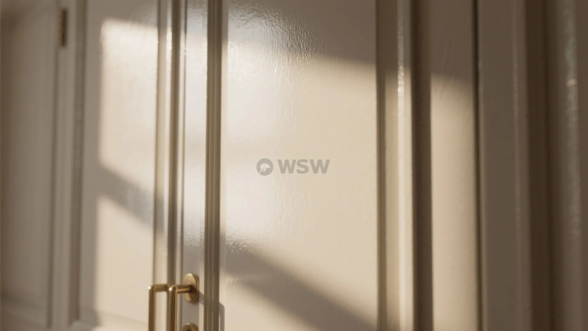 Shiny white cabinet doors with gold handles reflecting natural sunlight in a bright modern kitchen