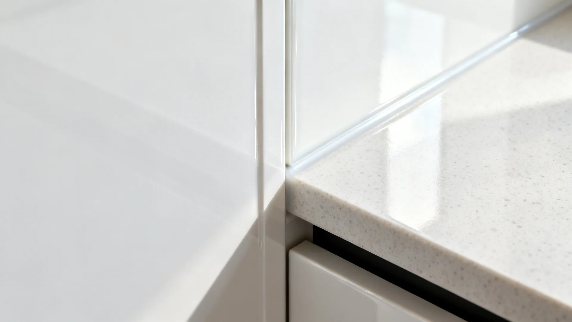 Macro detail of high-gloss white acrylic door edge with light quartz top.