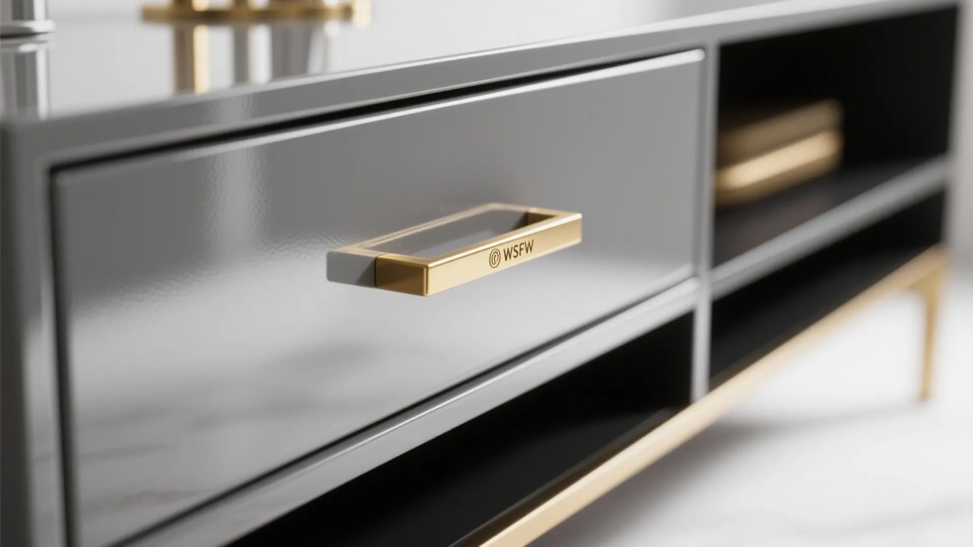 Close up of a glossy grey cabinet drawer featuring a luxury gold handle and frame