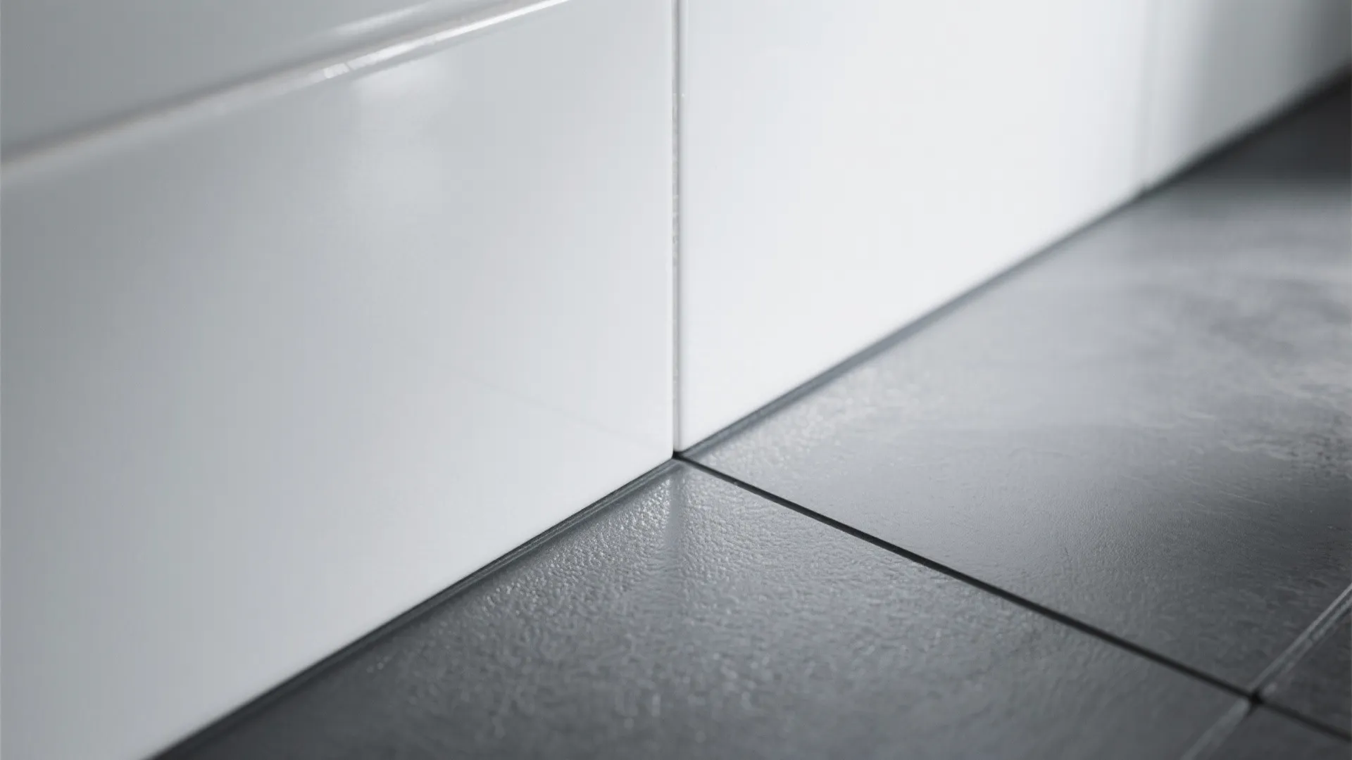 White glossy wall tiles meeting dark grey matte floor tiles in a clean modern bathroom