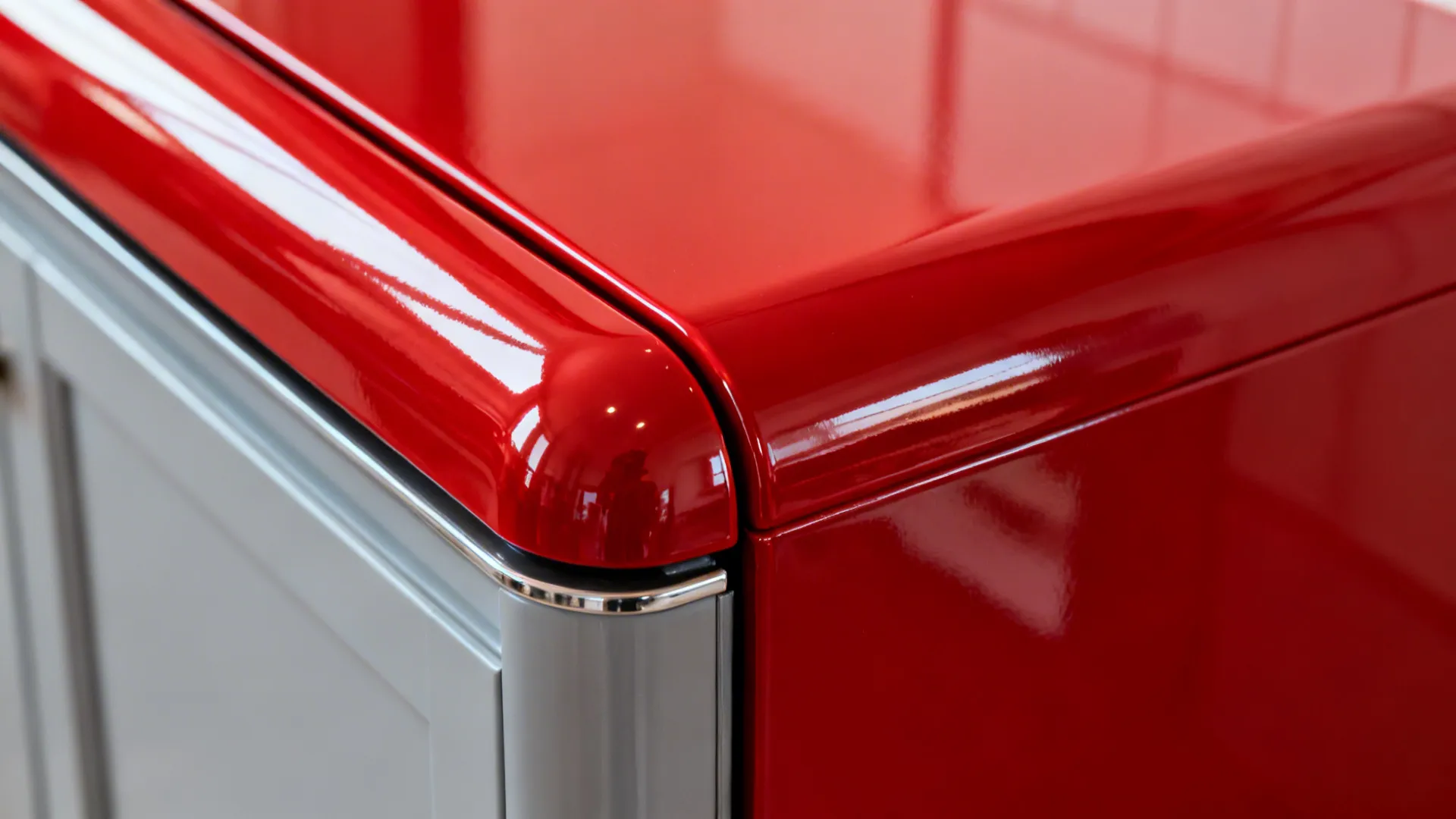 Macro of a glossy red appliance corner with clean curvature and bright highlights.