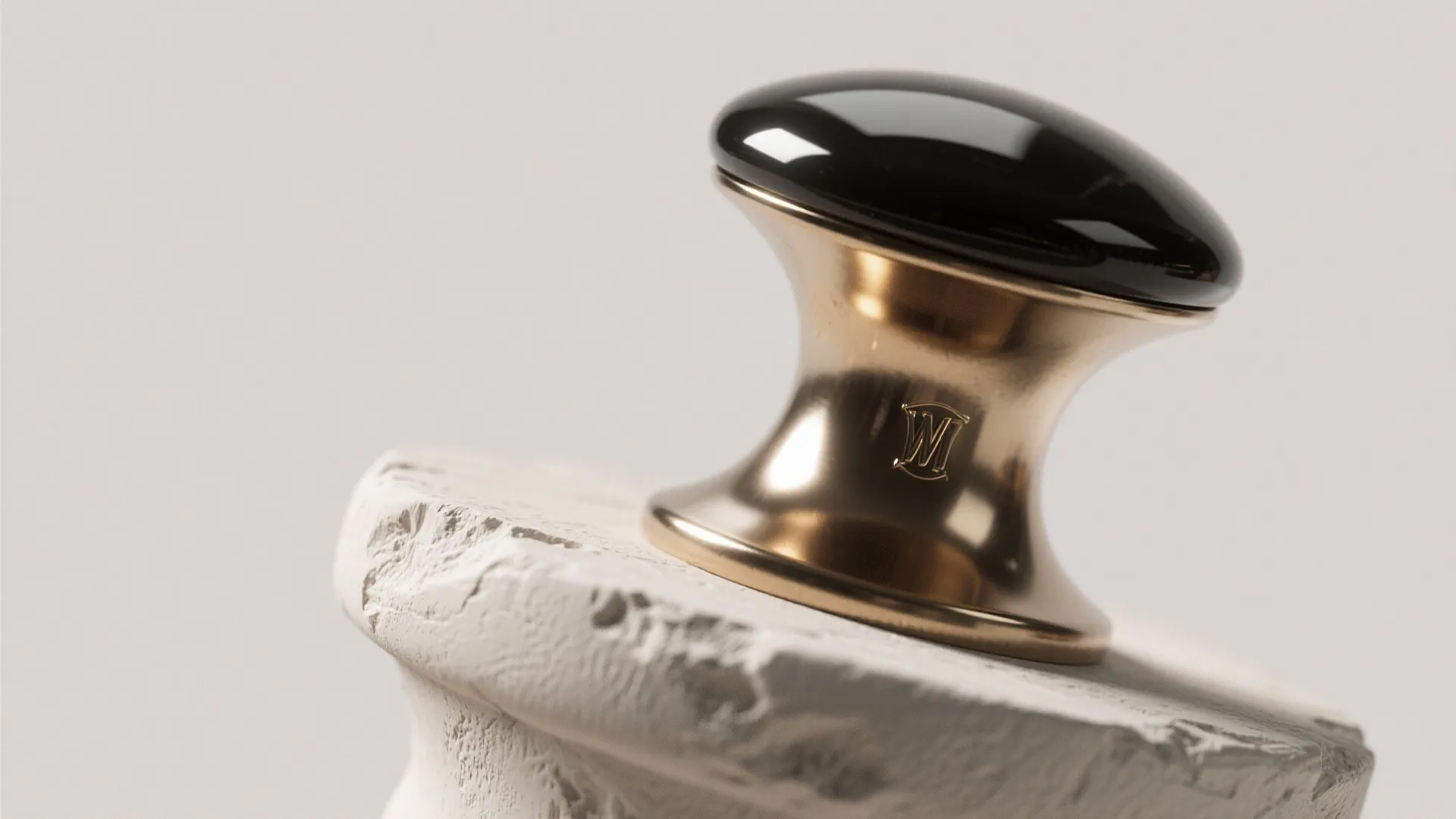 Black and gold cabinet knob sitting on a white textured stone surface with bright lighting
