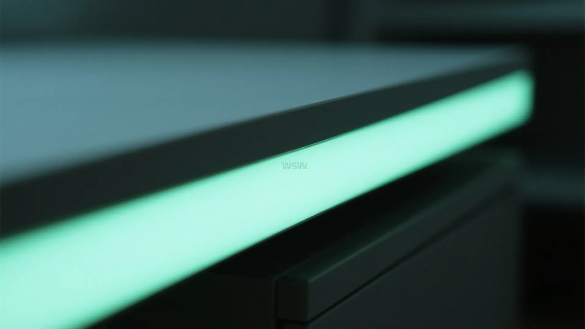 Close up of a dark grey table edge with integrated green glowing led light strip detail
