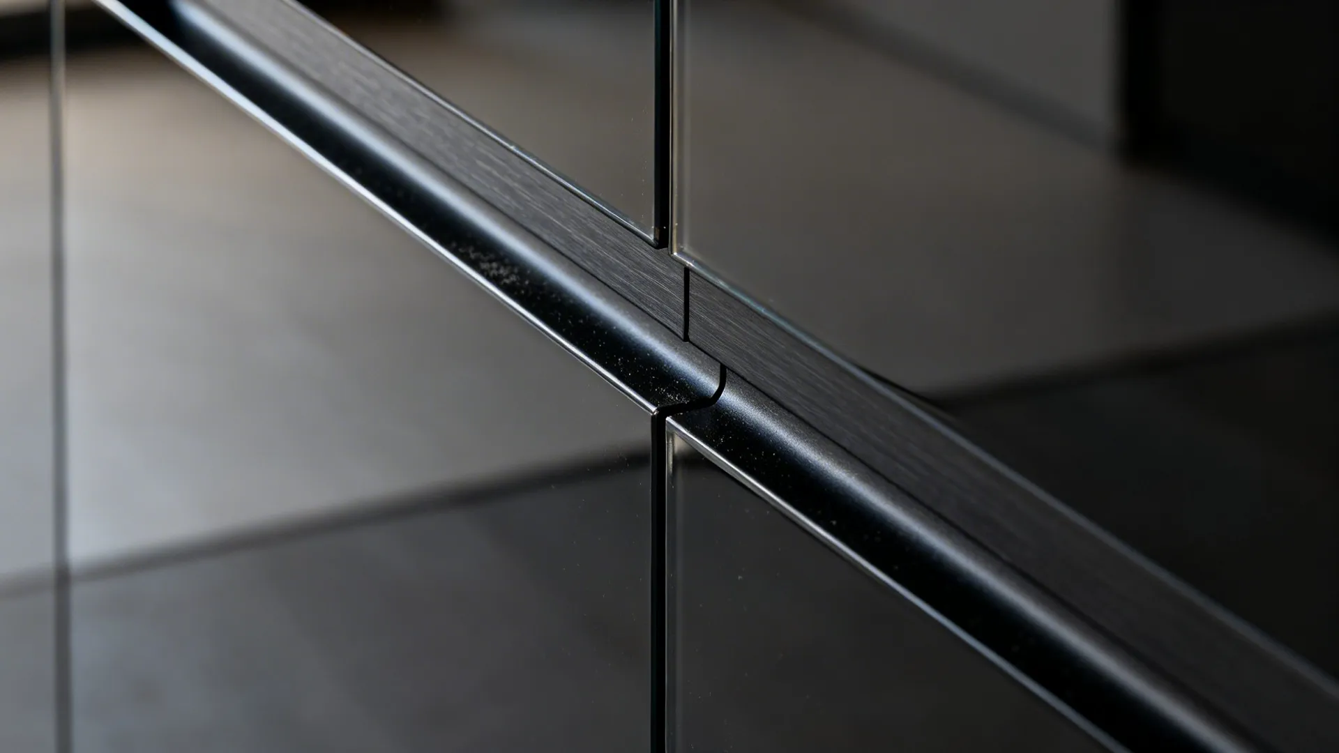 Macro view of anodized black Gola channel on glossy acrylic door.
