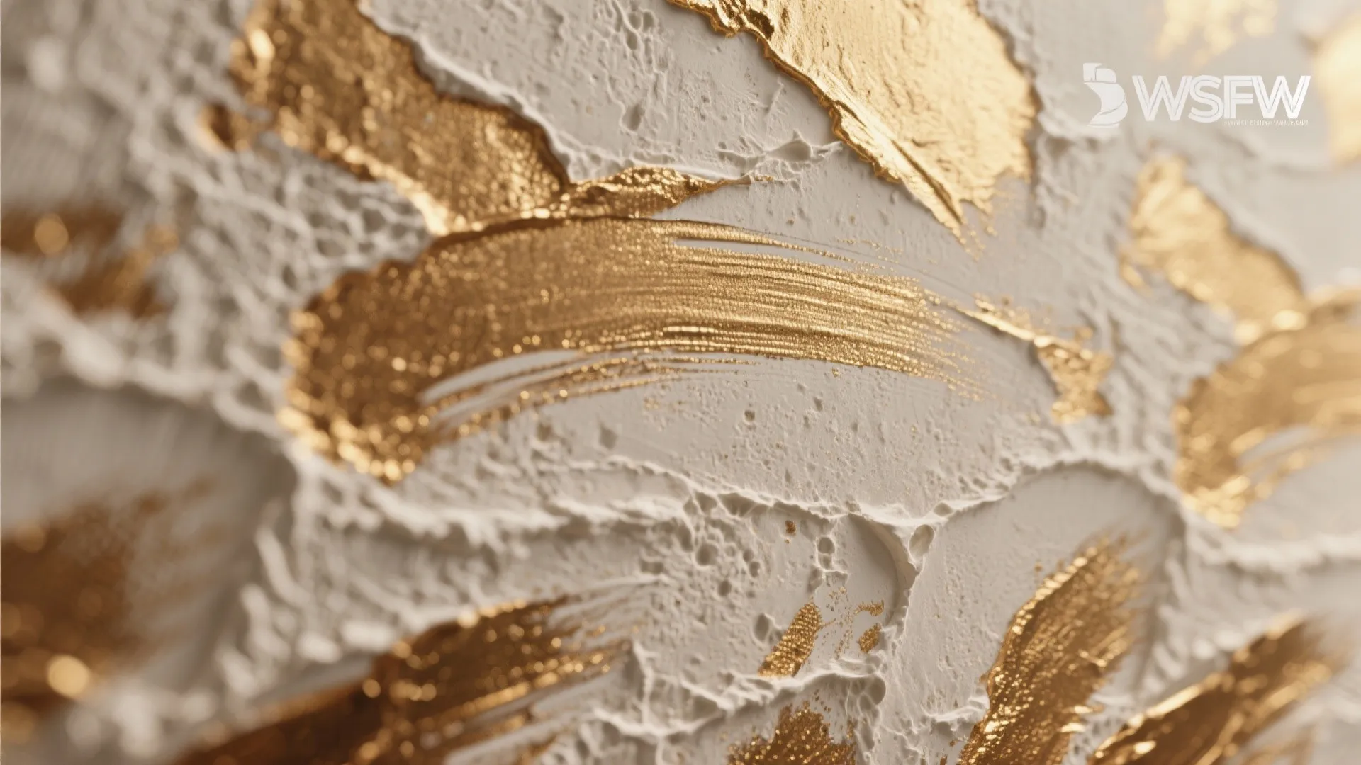 Close-up of textured plaster with a layered gold glaze showing brush strokes and depth.