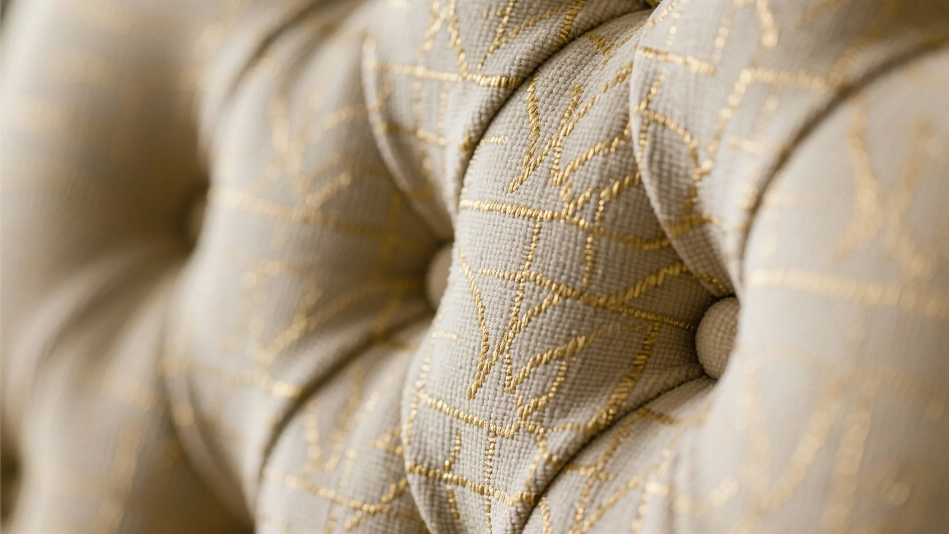 Close up of beige sofa fabric with gold thread patterns and small buttons for decoration