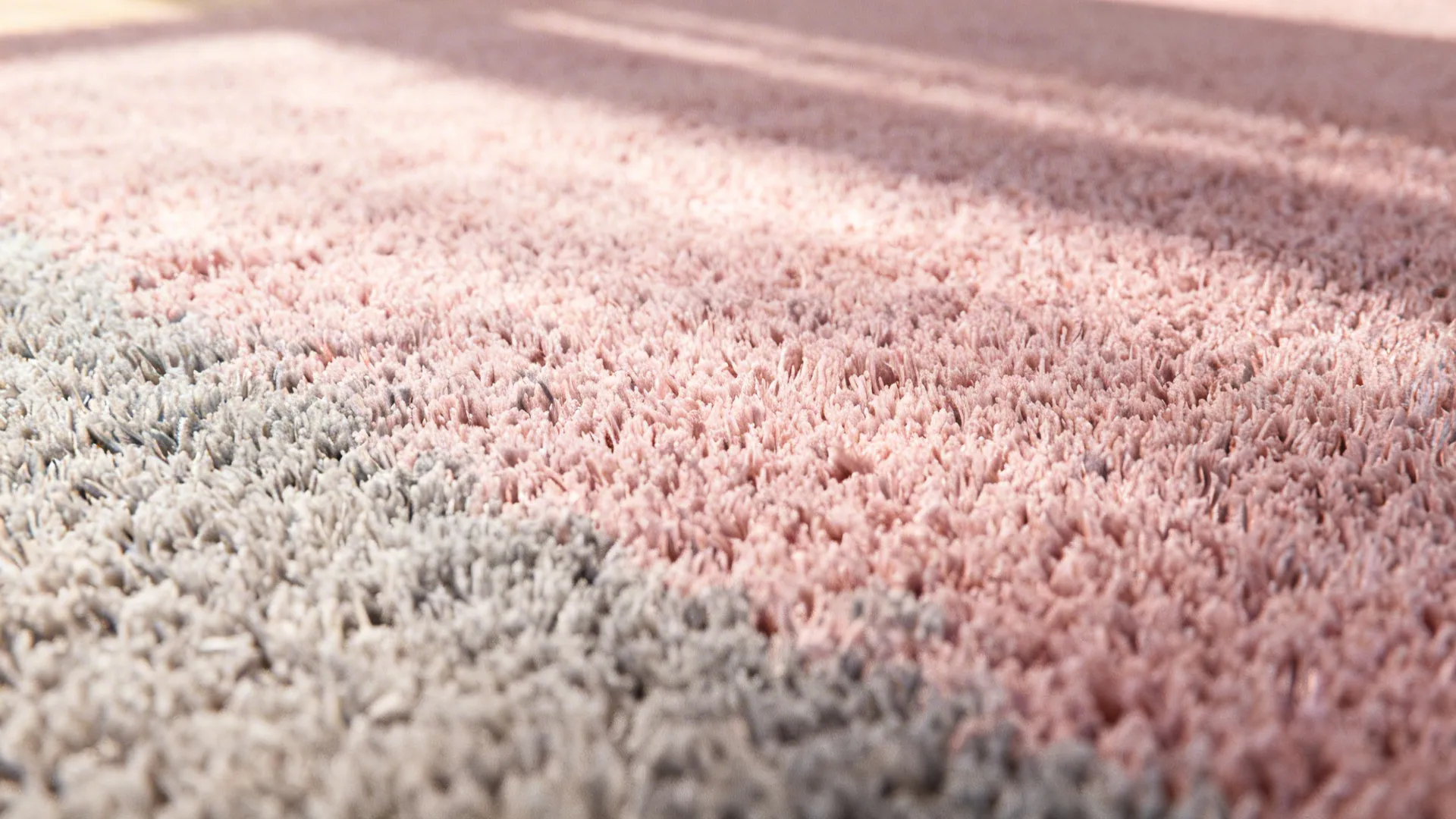Macro texture of a pink-to-grey gradient rug showing fiber detail and subtle color shift