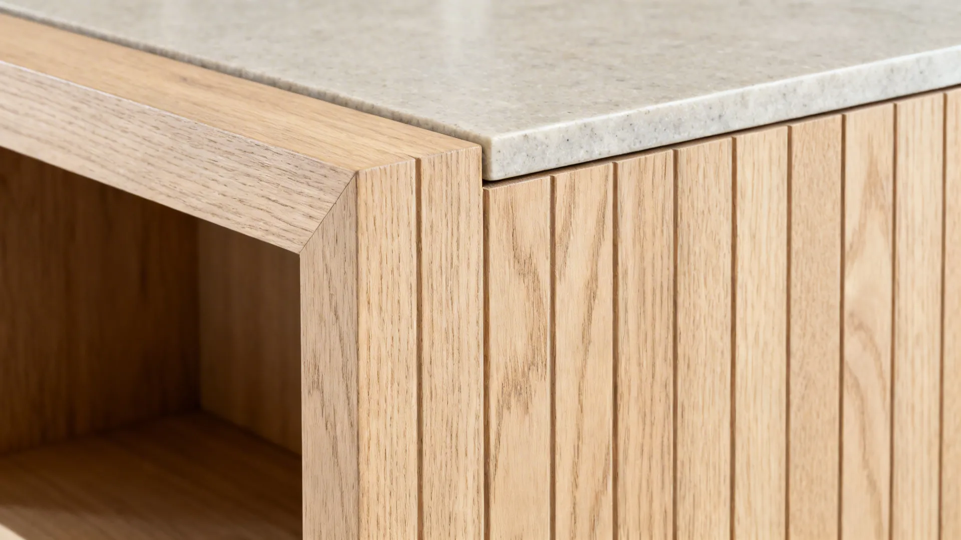 Close-up of aligned pale oak grain meeting a honed stone top with bookshelf edge.