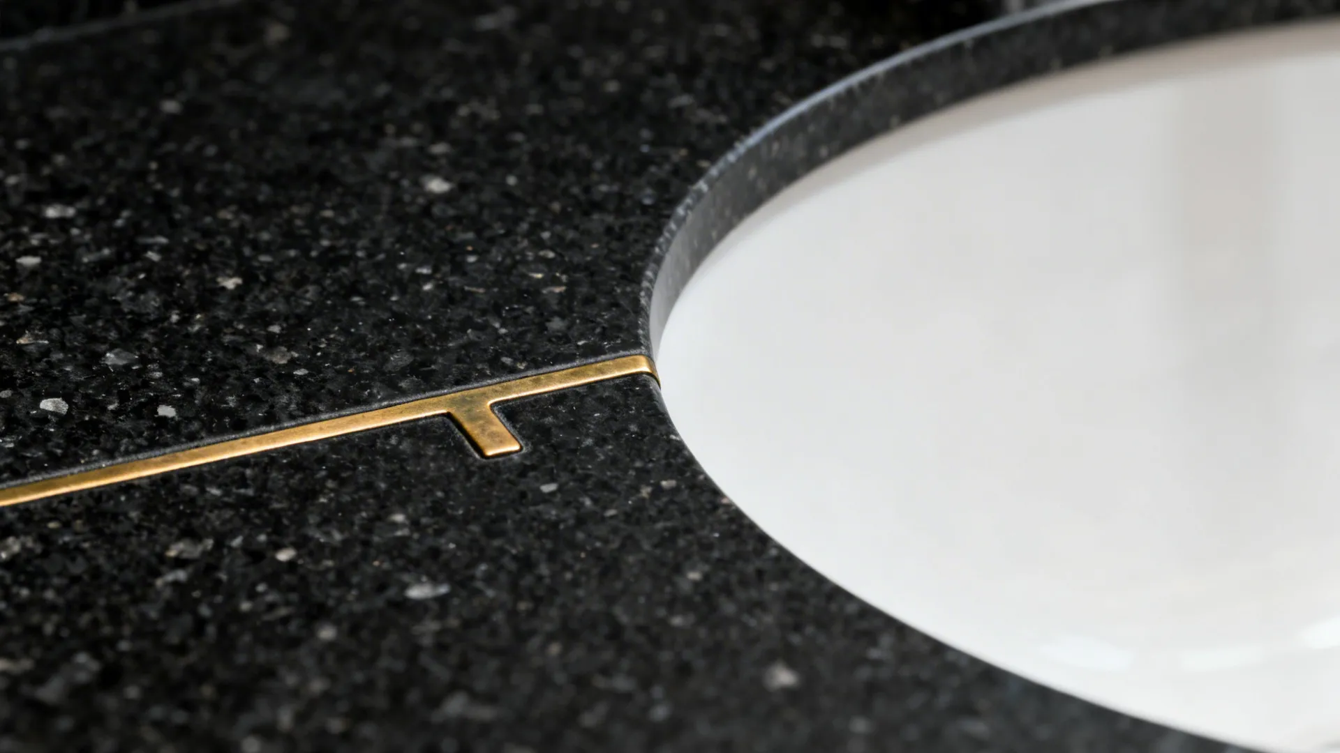 Close-up of honed black granite with a slim brass inlay and rounded edge.