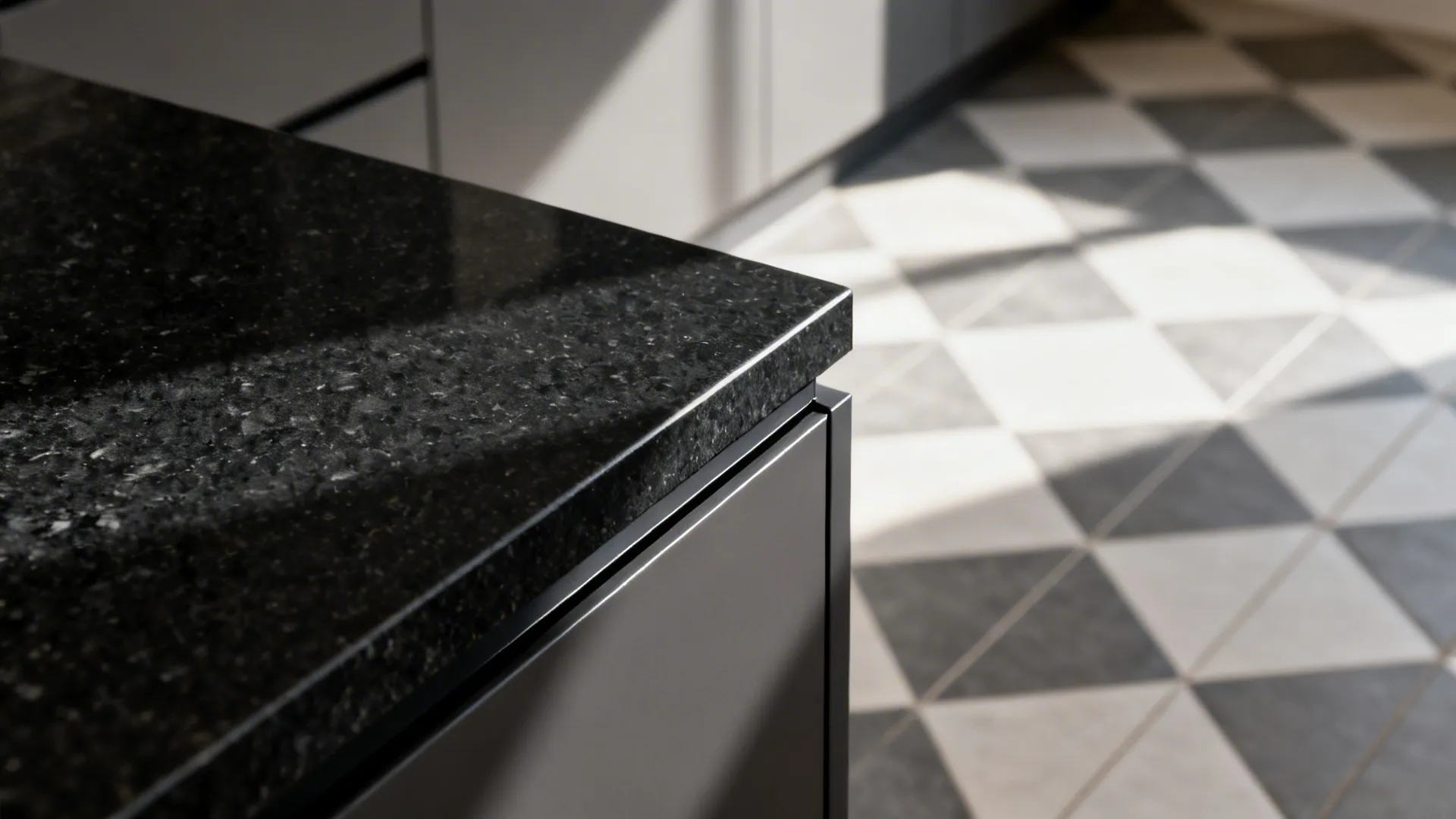 Macro of a micro-bevel Absolute Black granite edge meeting a calm checker tile floor.
