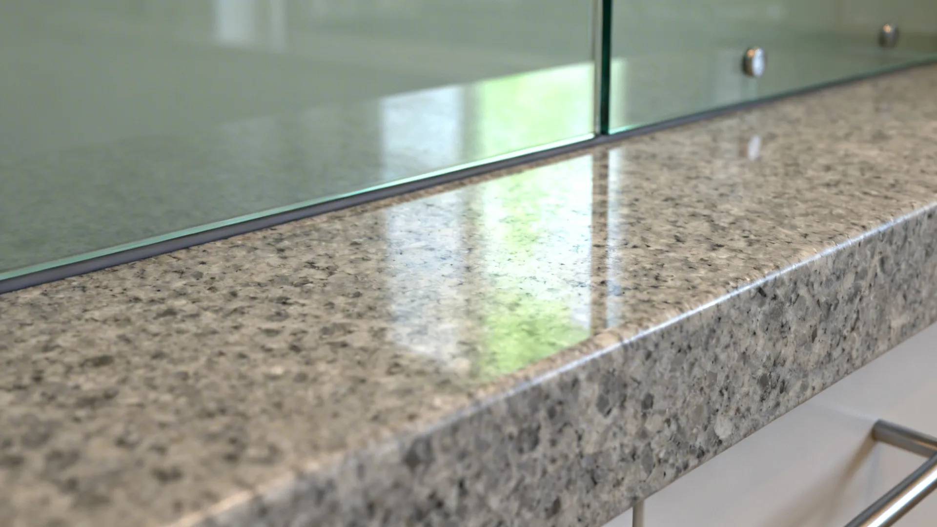 Macro detail of mid-tone granite meeting low-iron glass backsplash with a clean silicone seam.