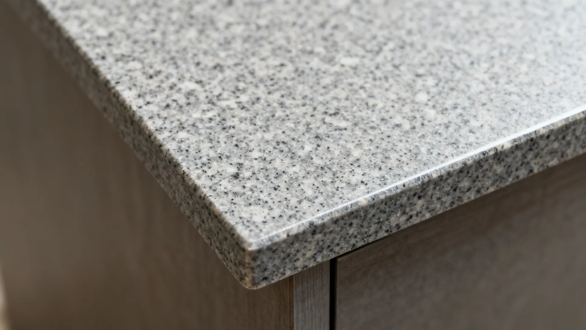 Macro of honed steel-grey granite with fine speckled texture and clean edge.