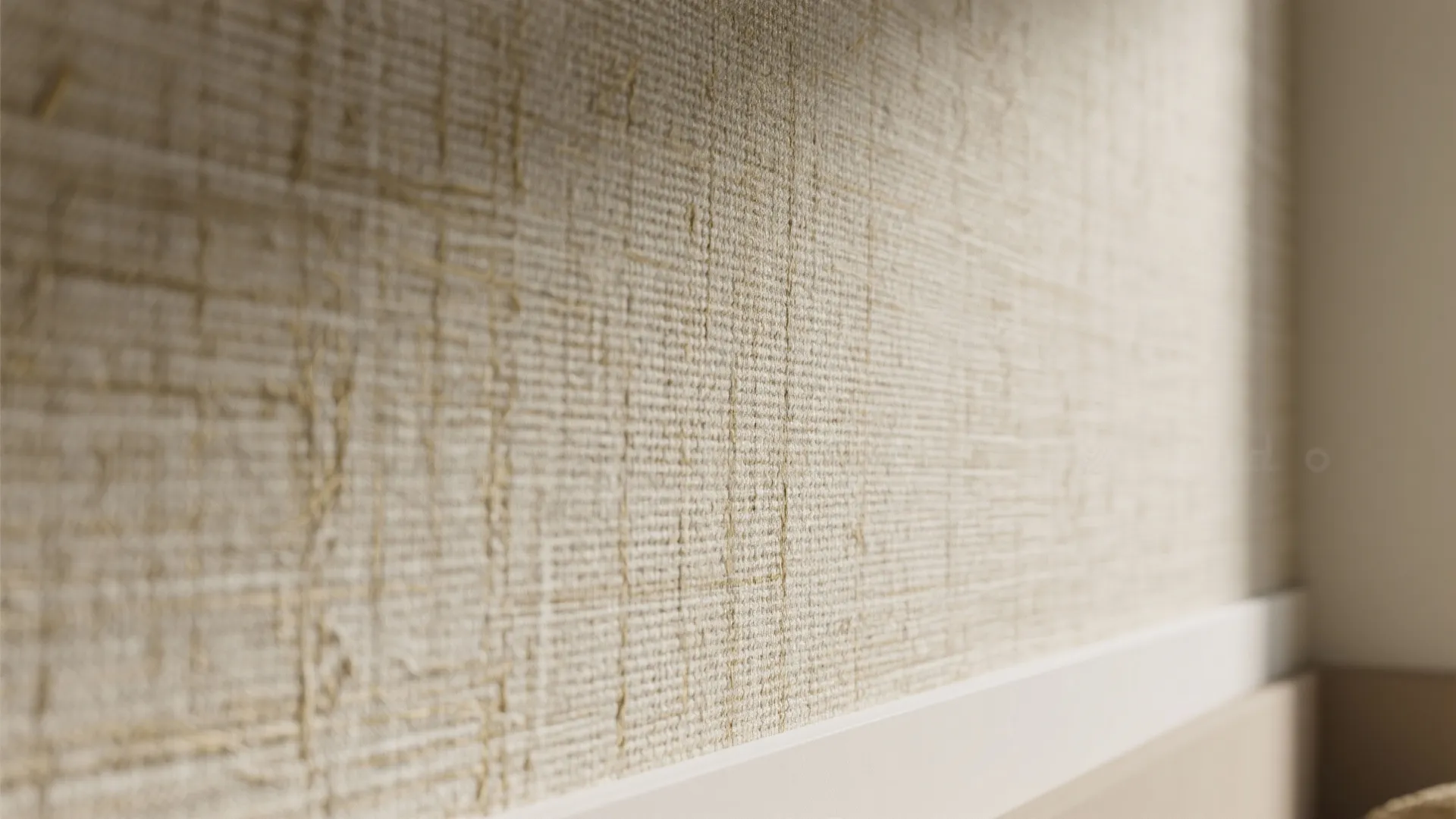 Close up view of textured beige fabric wallpaper on a wall with white wooden trim