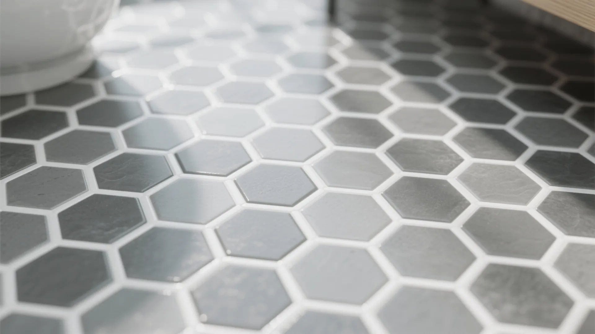 Close up of gray and white hexagon floor tiles in a modern bathroom with natural sunlight