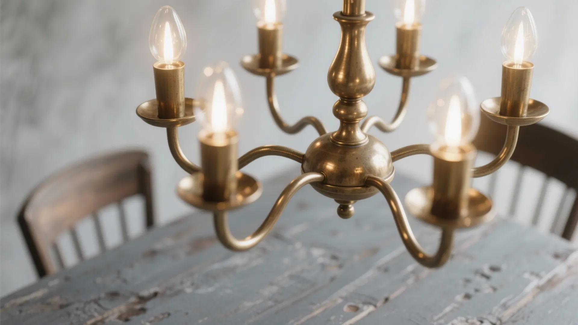 Close up of a classic brass ceiling light with lit bulbs over a rustic table