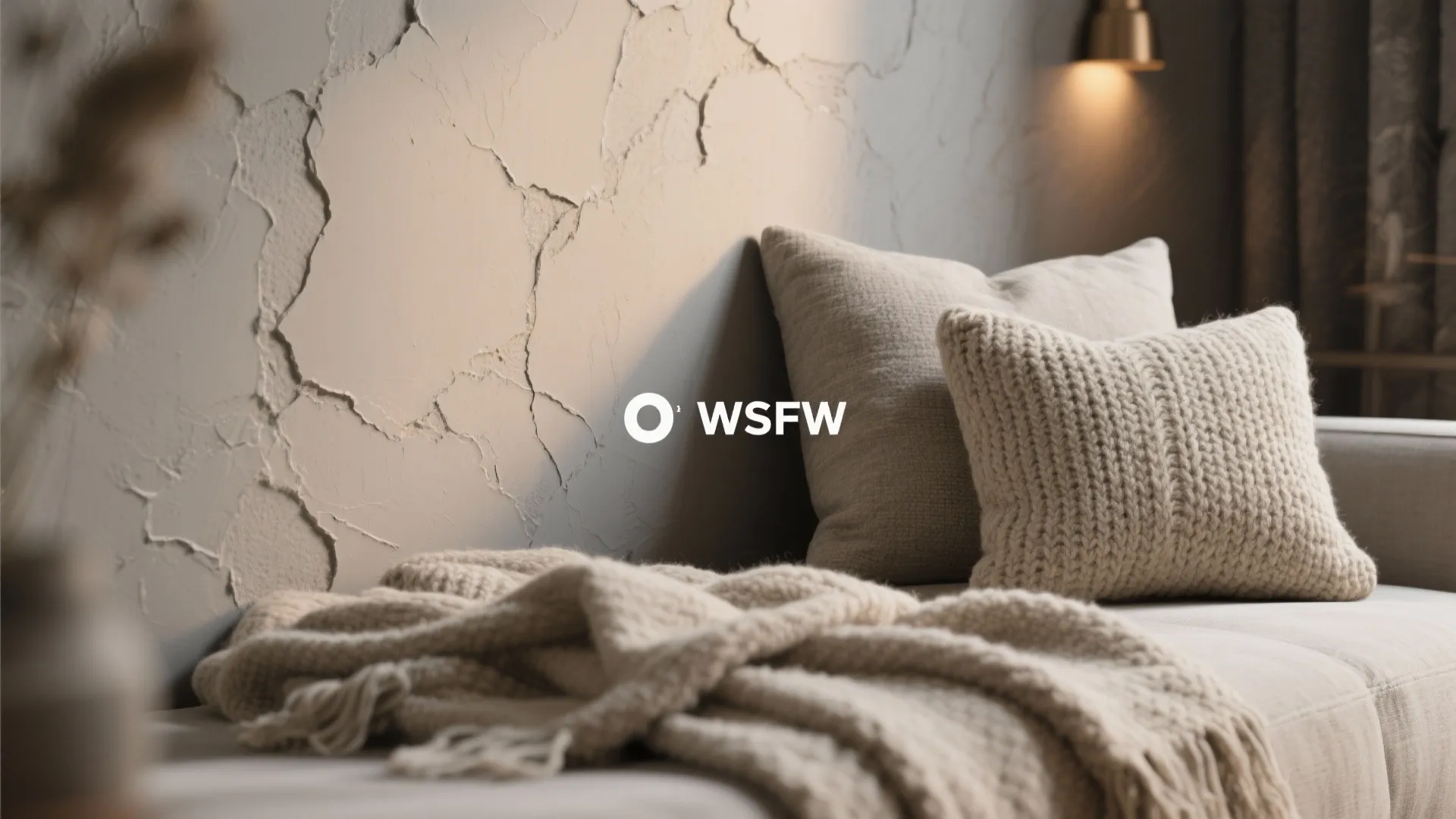 Cozy living room detail with textured wall panel soft pillows and a warm knit blanket