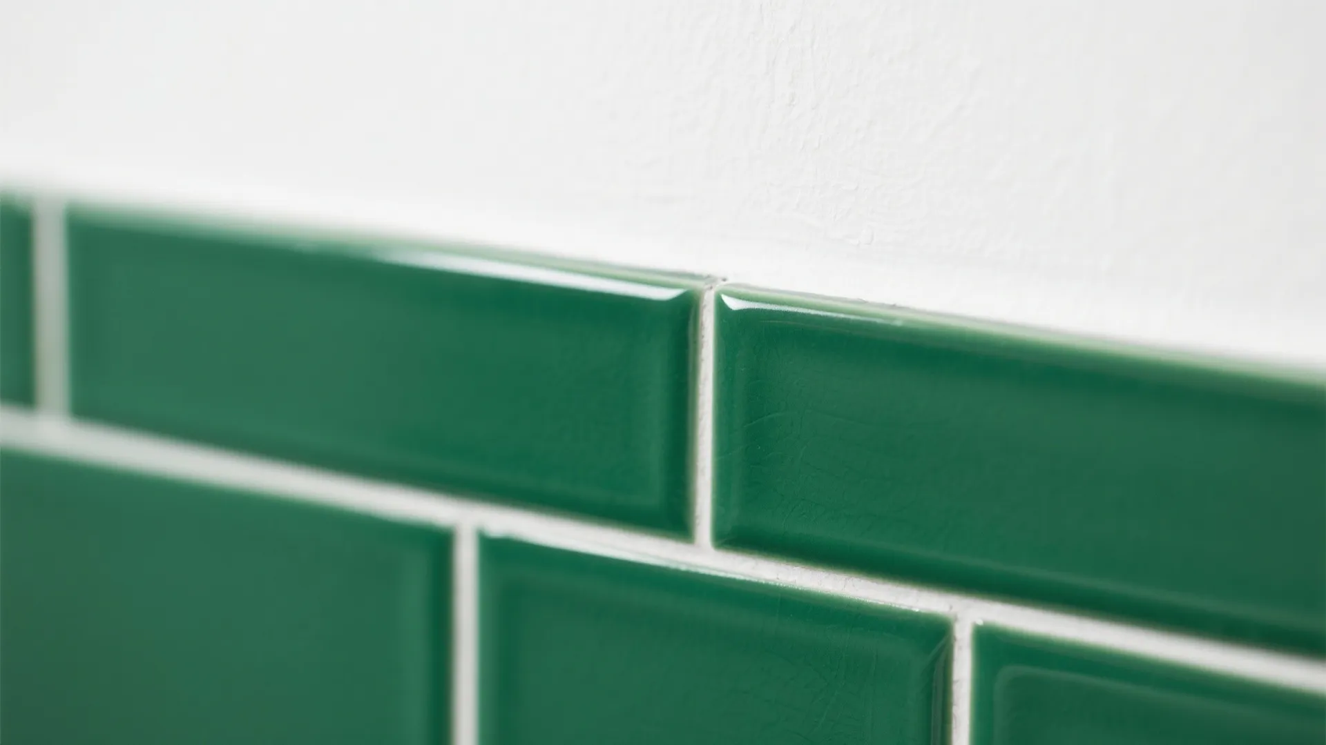 Close up of green rectangular wall tiles with white grout against a clean white wall