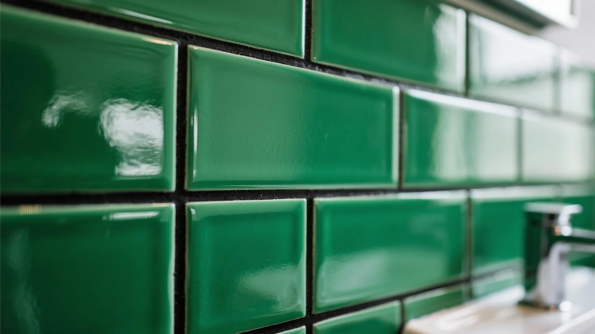 Close up of shiny green wall tiles with black grout lines in a modern bathroom
