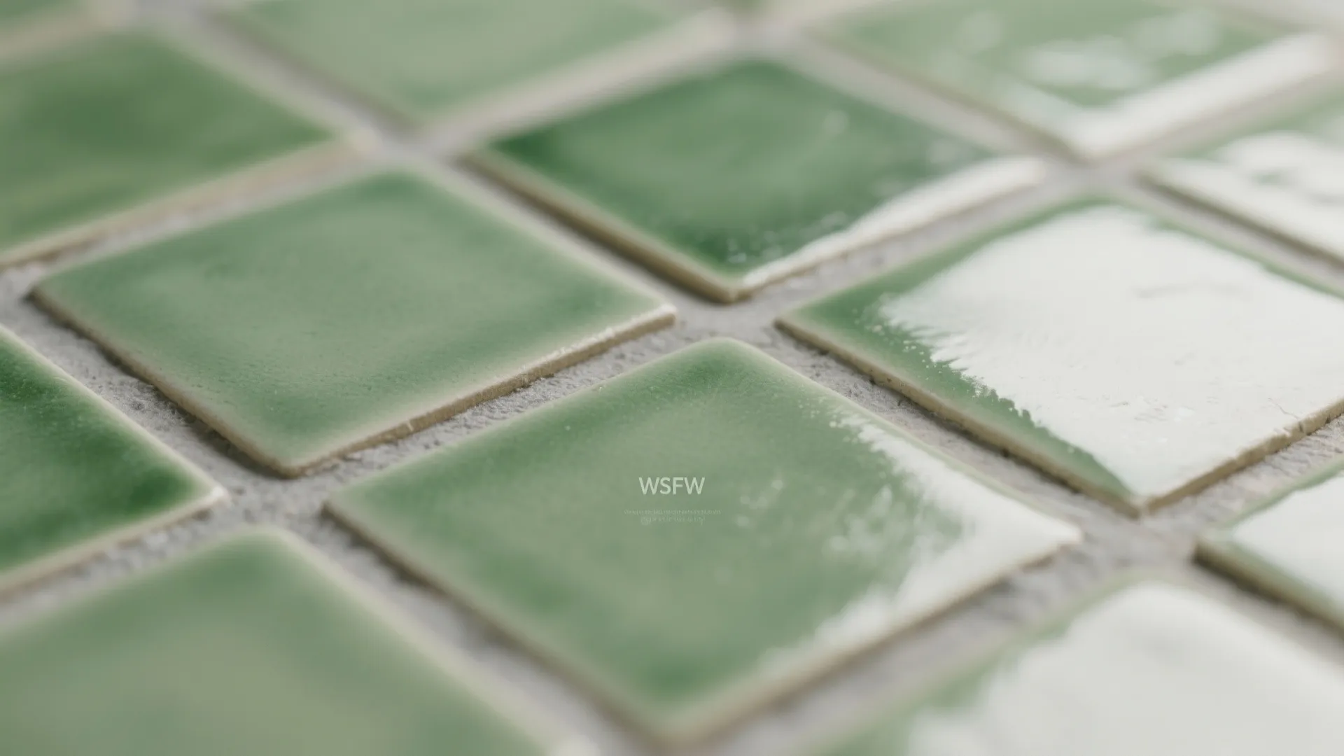 Close up view of glossy green square wall tiles with light grey grout in bathroom